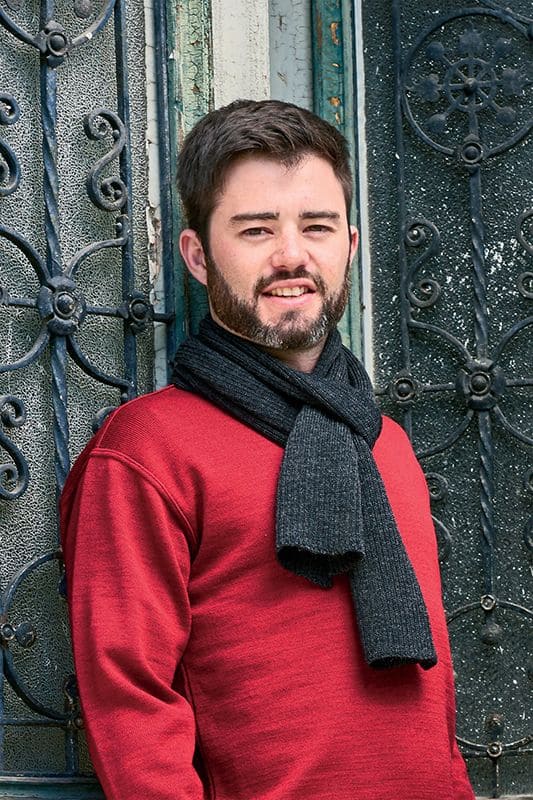 Mann mit rotem Pulli trägt dunkelgrauen Schal aus bio Wolle (kbT) vom Finkhof