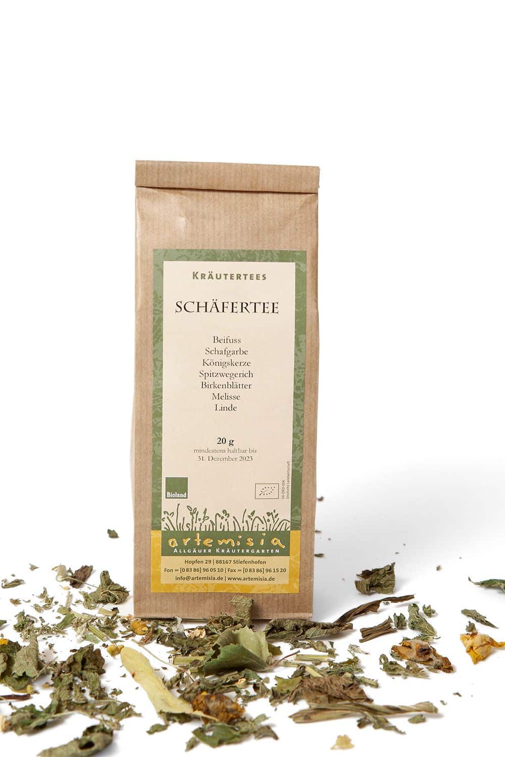 Schäfertee in 20g Verpackung auf weißem Untergrund mit getrockneten Kräutern davor