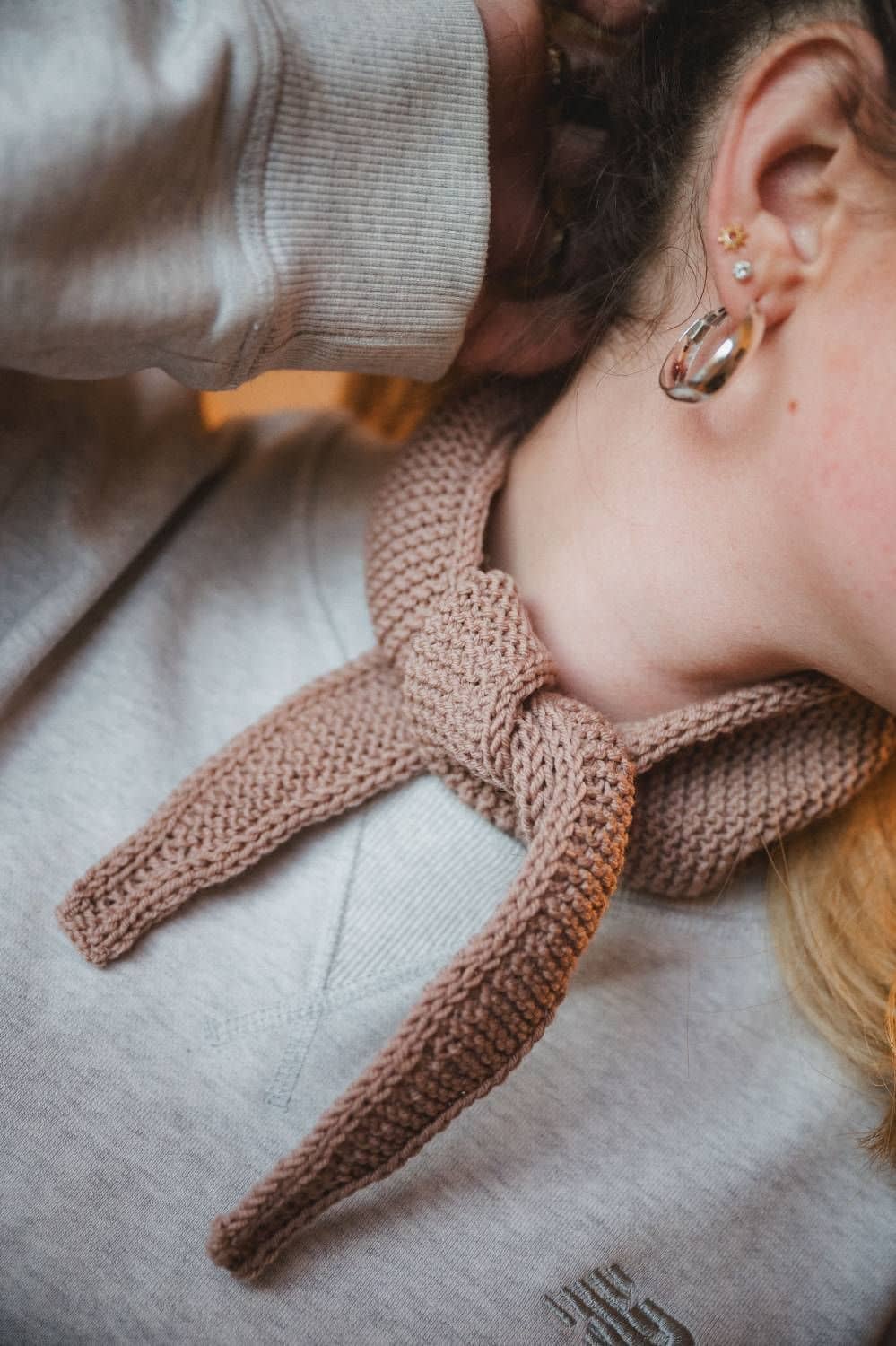 Bildausschnitt von Frau mit großem silberfarbenem Ohrring, und rosafarbenem Mini-Schal aus einer Wolle vom Finkhof