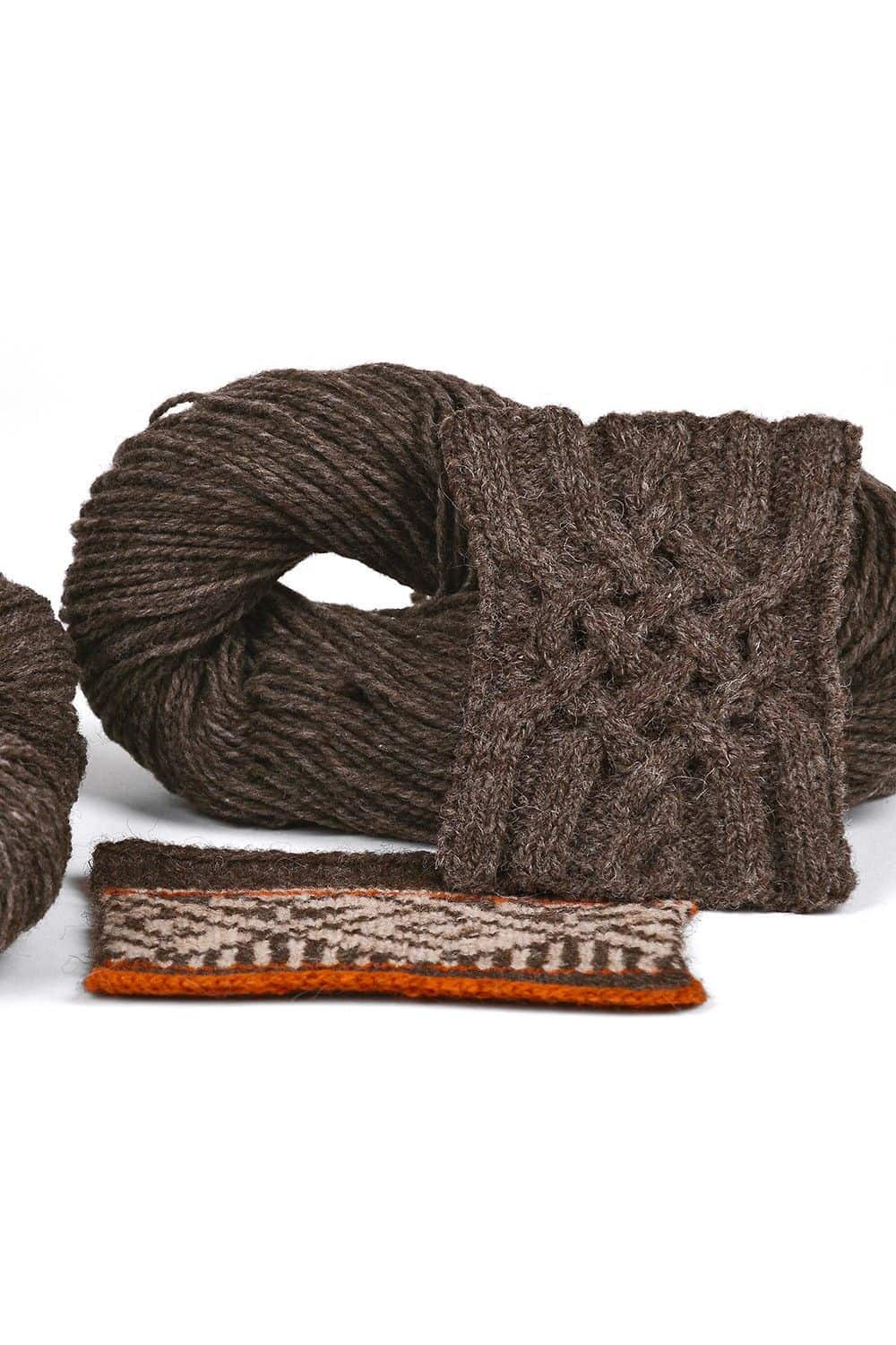 Knäul dicke ungefärbte Merinowolle in graubraun vom Finkhof aus bio Wolle (kbT) mit Strickstücken davor