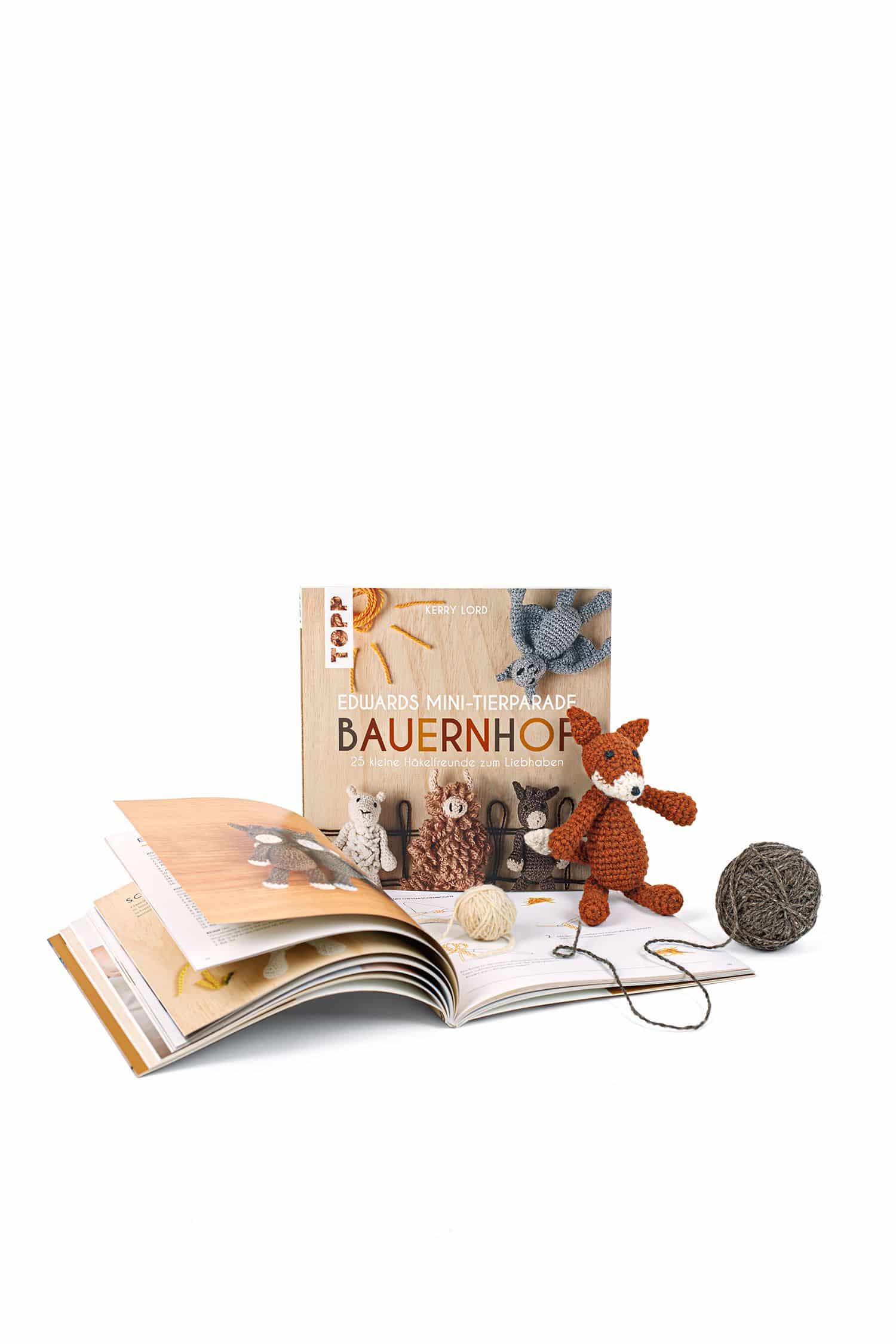 Edwards Mini-Tierparade. Bauernhof Buch ,,Edwards Mini Tierparade. Bauernhof" mit aufgeschlagenem Exemplar und gestricktem Tier davor