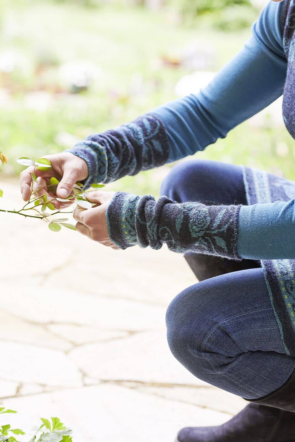 Armstulpen Rose Armstulpen Rose mit floralem Muster in Blautönen aus bio Wolle (kbT) an Hand, die Ast hält