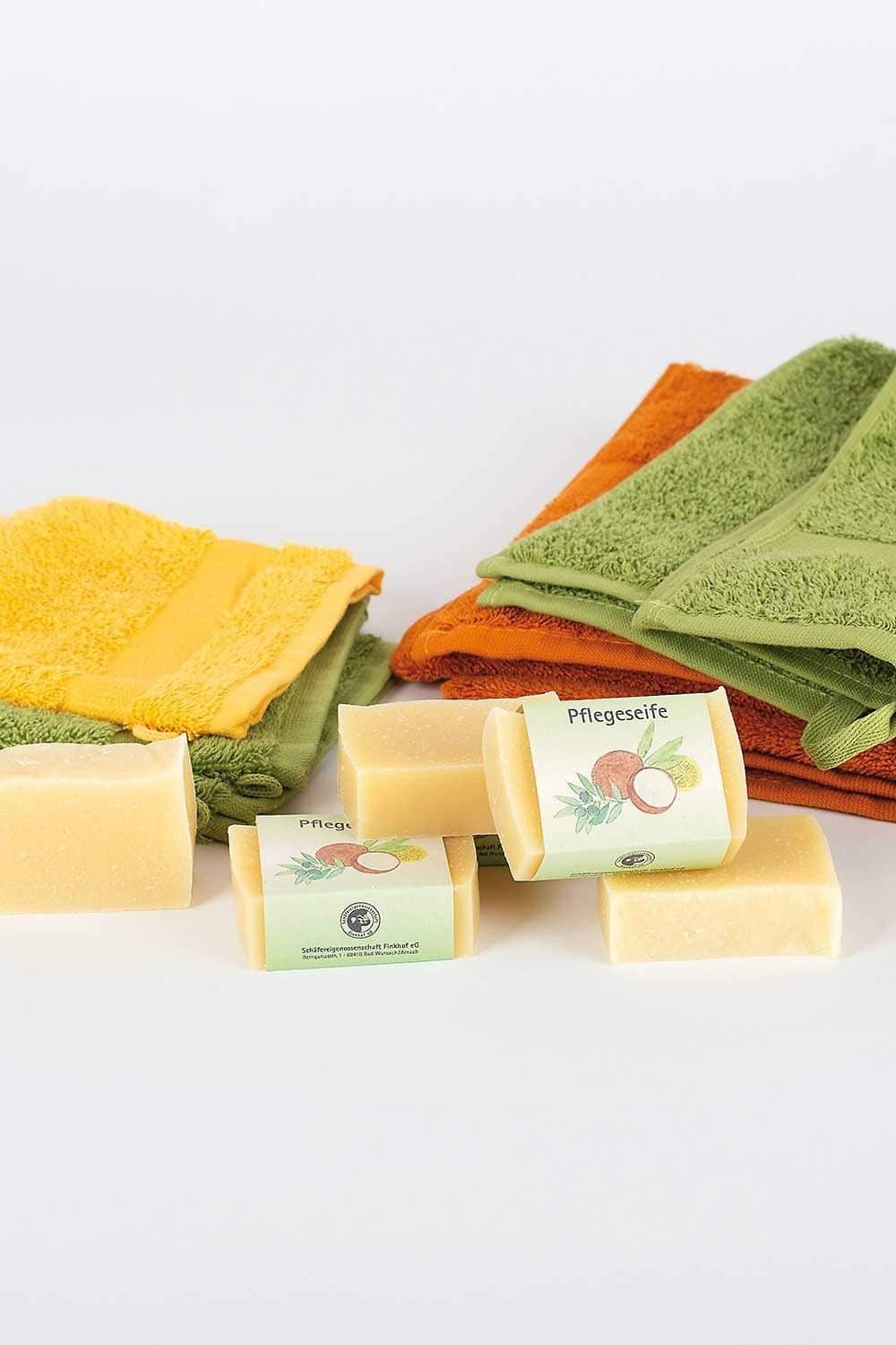 Finkhof Pflegeseife Zitrus – milde Naturseife mit Wollfett & Pflanzenölen, dekoriert auf bunten Handtüchern