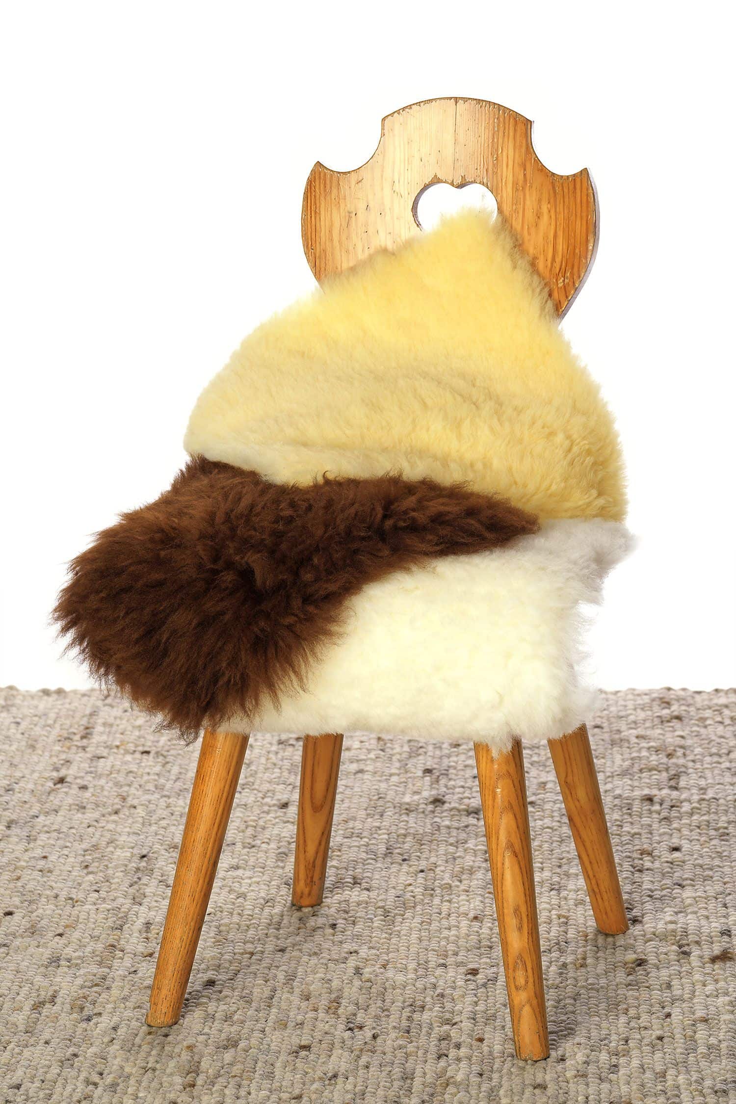 Stuhlauflage quadratisch relugan gegerbte Stuhlauflagen in quadratischer Form vom Finhof liegen in verschiedenen Farben auf Stuhl übereinander