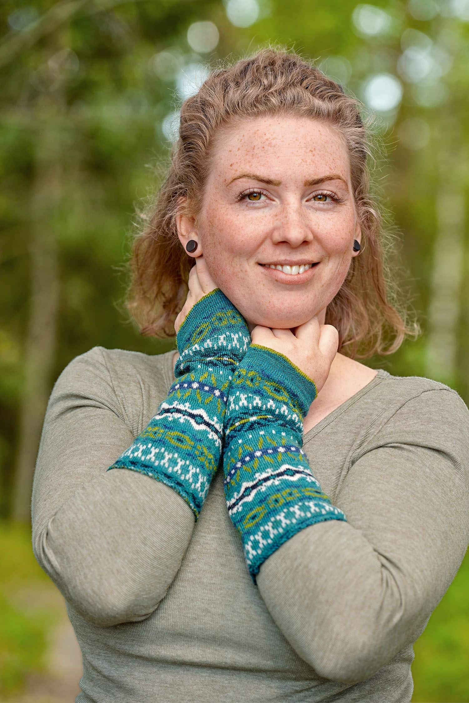 Armstulpen Nordic Frau mit unifarbigem Shirt trägt türkise Armstulpen mit nordischem Muster aus bio Wolle (kbT)