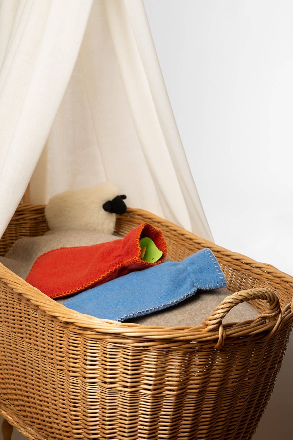 Wärmflaschenbezug klein (kbT) rote und blaue Wärmflaschenhülle aus bio Wolle (kbT) vom Finkhof in Stubenwagen mit Wolldecke und Plüschschaf