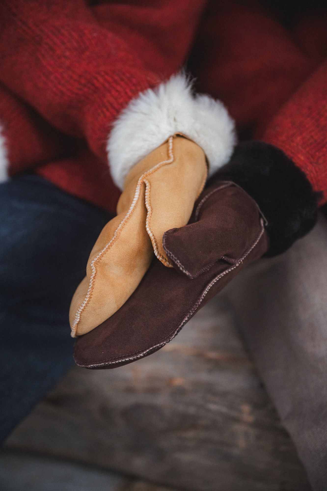 Paar hell- und dunkelbraune Fellhandschuhe ohne Bund aus Schaffell und Pelzvelour liegen auf braunem Kork