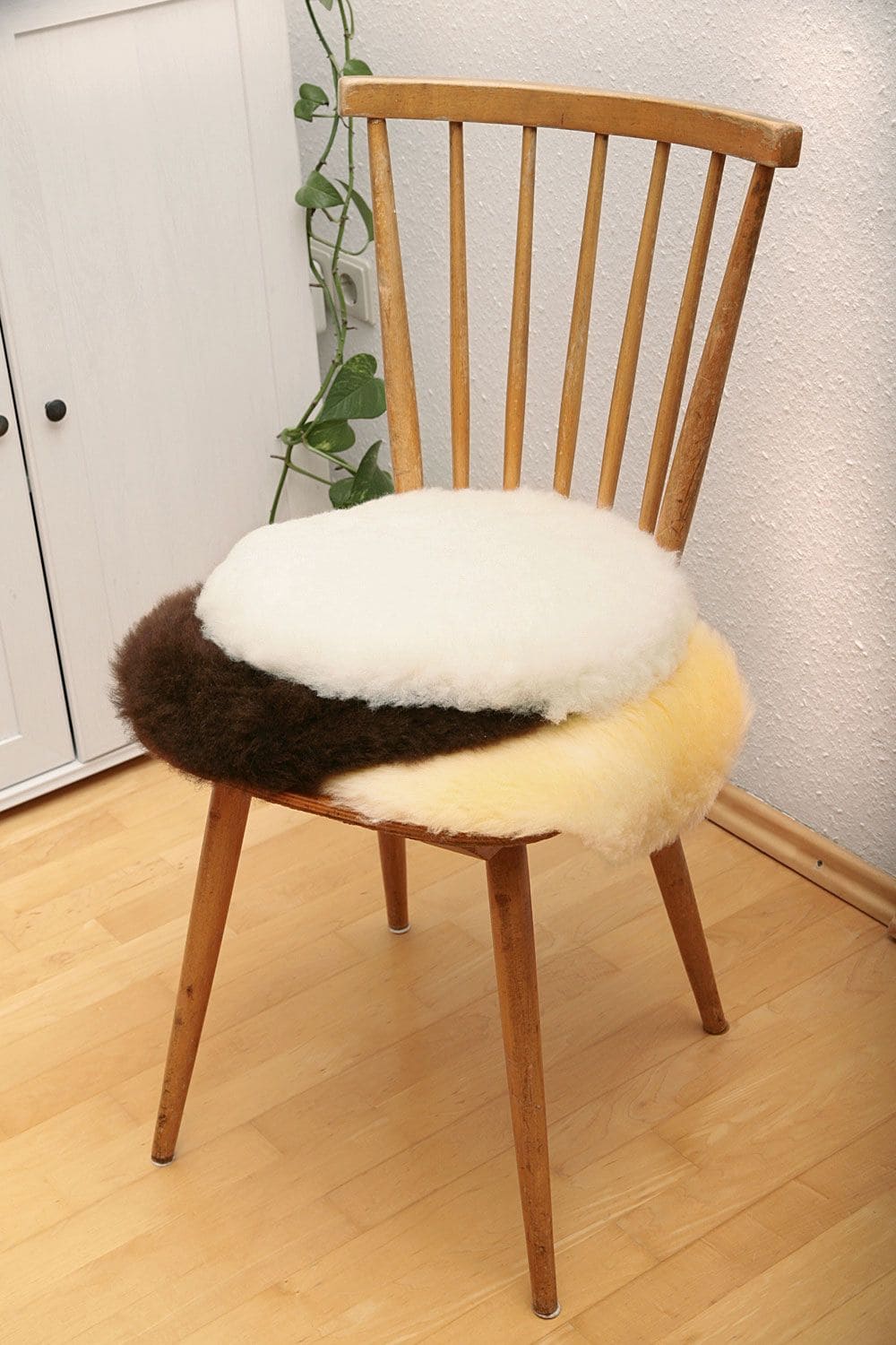Stuhlauflage rund runde Stuhlauflagen aus Schaffell vom Finkhof in braun, weiß und gelblich auf Stuhl gestapelt