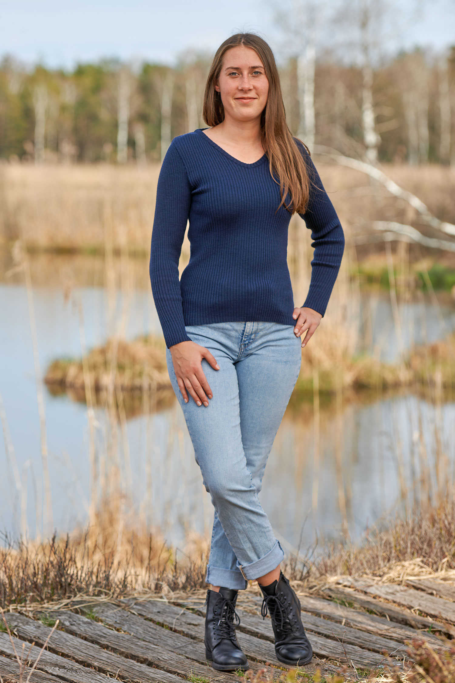 V-Shirt Rippe aus reiner Bio-Schurwolle Frau mit Jeans und marineblauem Shirt aus Rippstoff vom Finkhof aus bio Wolle (kbT) steht auf einem Steg