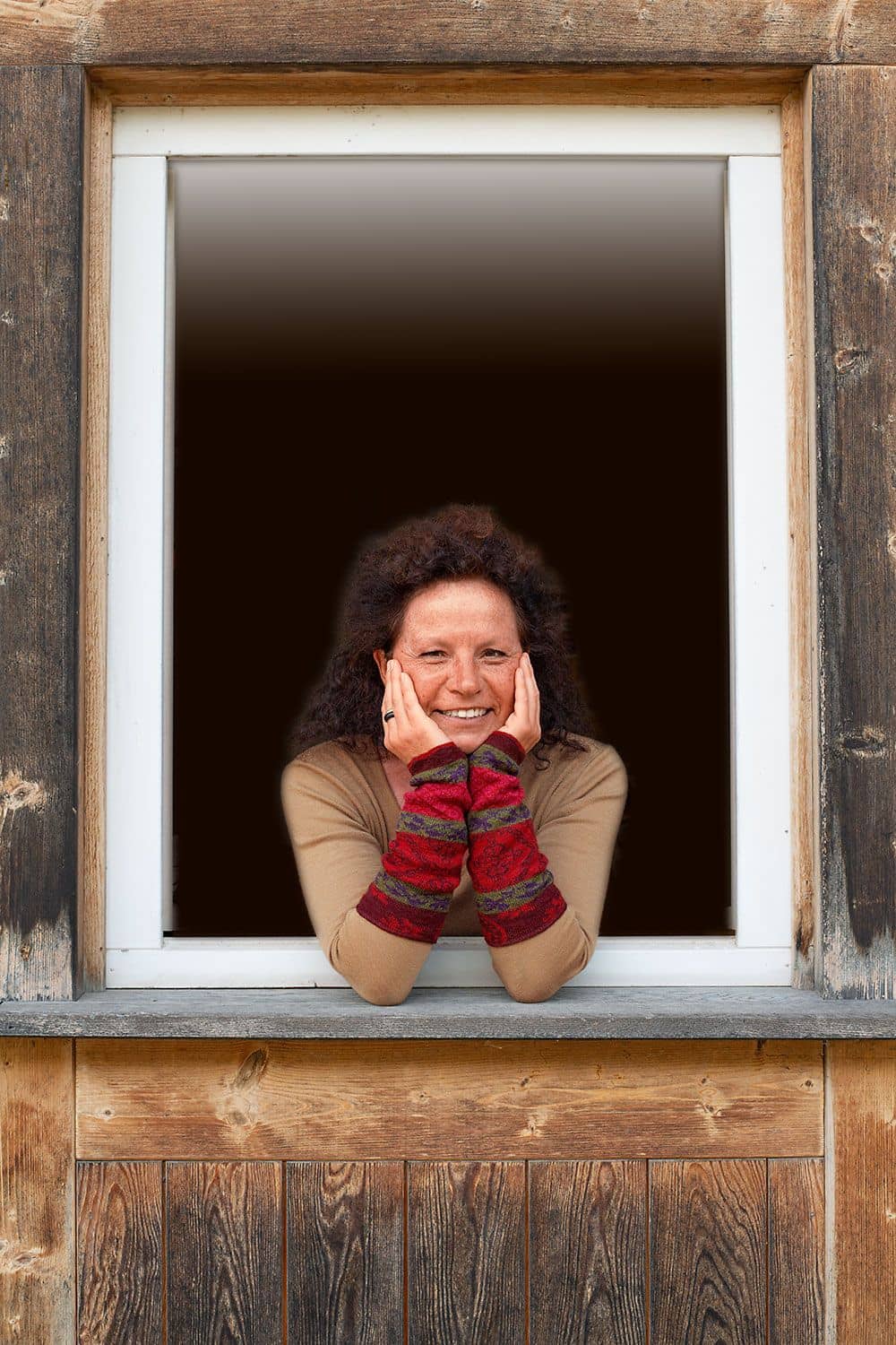 Frau mit braunem Shirt und burgunderfarbenen Armstulpen mit nordic Muster aus bio Wolle (kbT) schaut aus Fenster