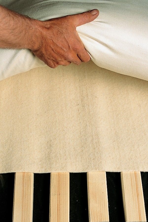 Finkhof Matratzenschoner in naturweiß aus bio Wolle (kbT) mit 100x200cm liegt auf einem Rost, Matratze wird draufgelegt