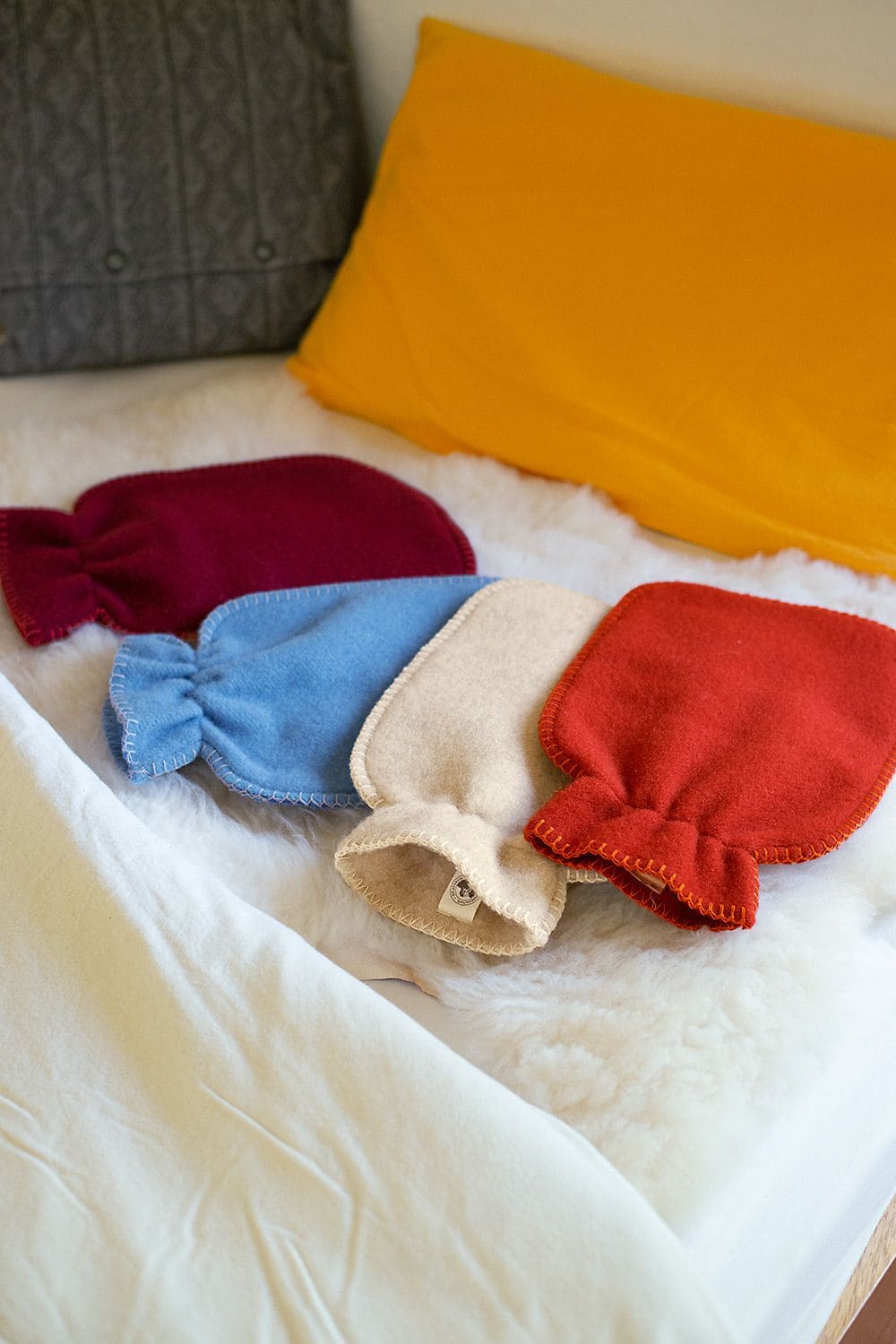 Wärmflaschenbezug groß (kbT) große einfarbige Wärmflaschenbezüge in verschiedenen Farben aus bio Wolle (kbT) vom Finkhof auf weißem Fell mit Kissen