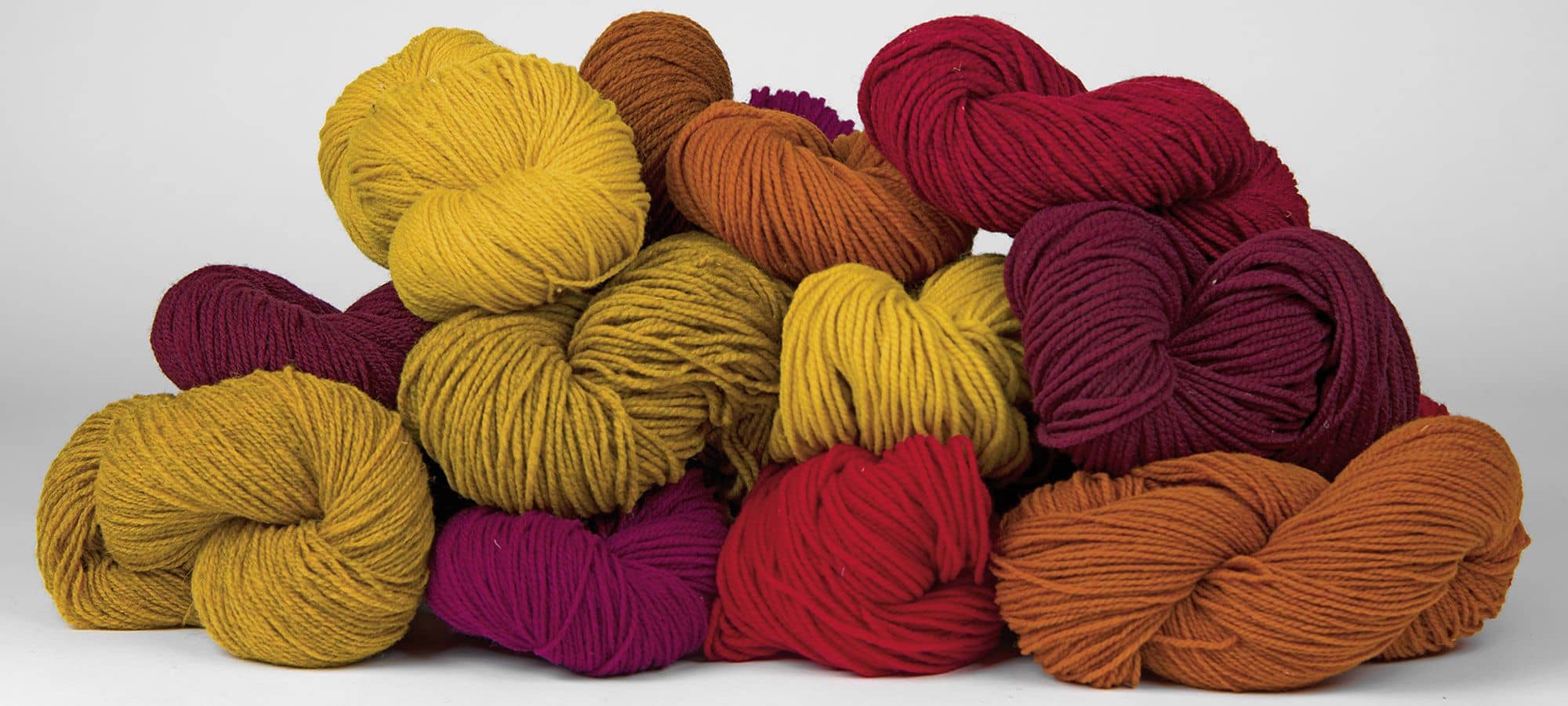 Wollen in Rot- und Gelbtönen liegen zur Pyramide aufgestapelt da