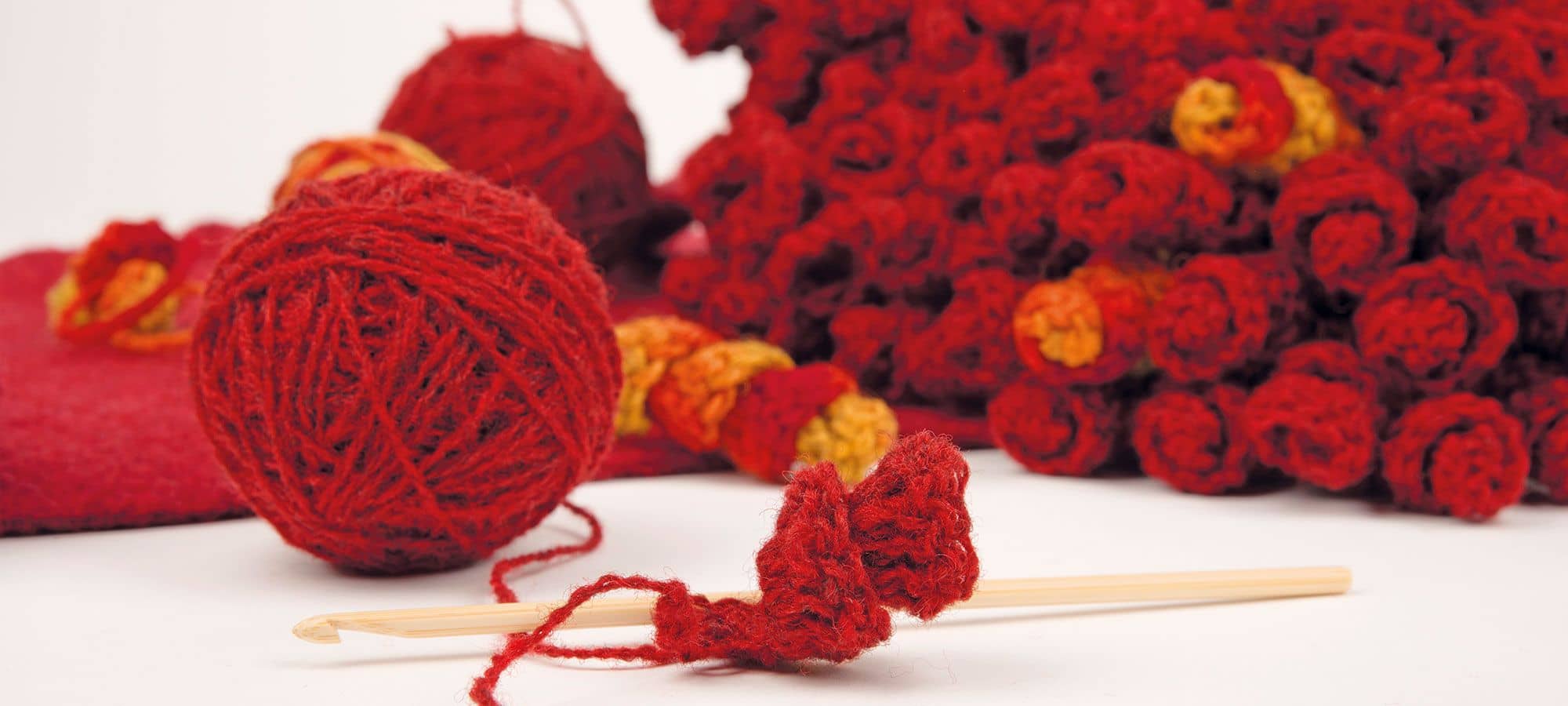 Finkhof Banner mit roten Häkelspiralen, Wollknäul und Häkelnadel