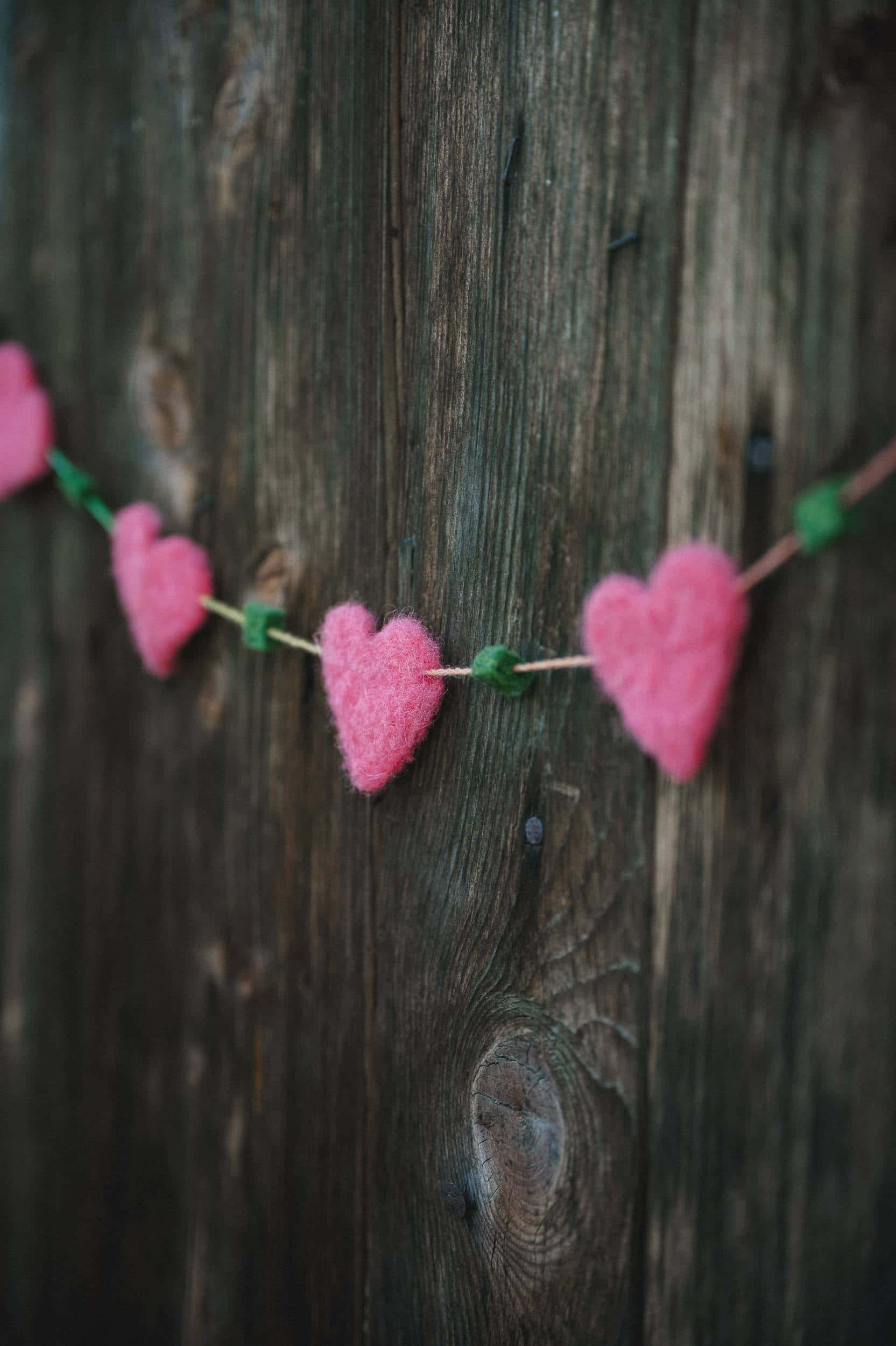 pinke Girlande aus Filzherzen zu Muttertag an einer Holzwand