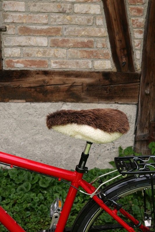 schmaler brauner pflanzlich gegerbter Sattelbezug vom Finkhof aus bio Wolle (kbT) und Schaffell auf rotem Fahrrad