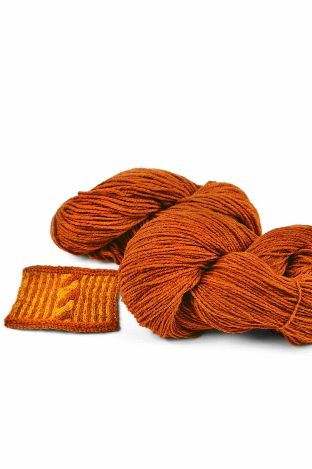 dicke orangemelierte Finkhof Merinowolle aus bio Wolle (kbT) mit Strickstück davor, weißer Untergrund