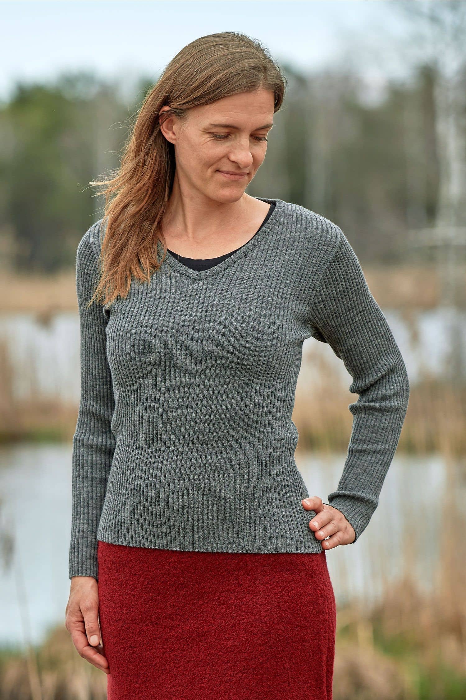 Frau trägt roten Rock und Pulli mit Rippstoff und V Ausschnitt aus bio Finkhof Wolle (kbT)