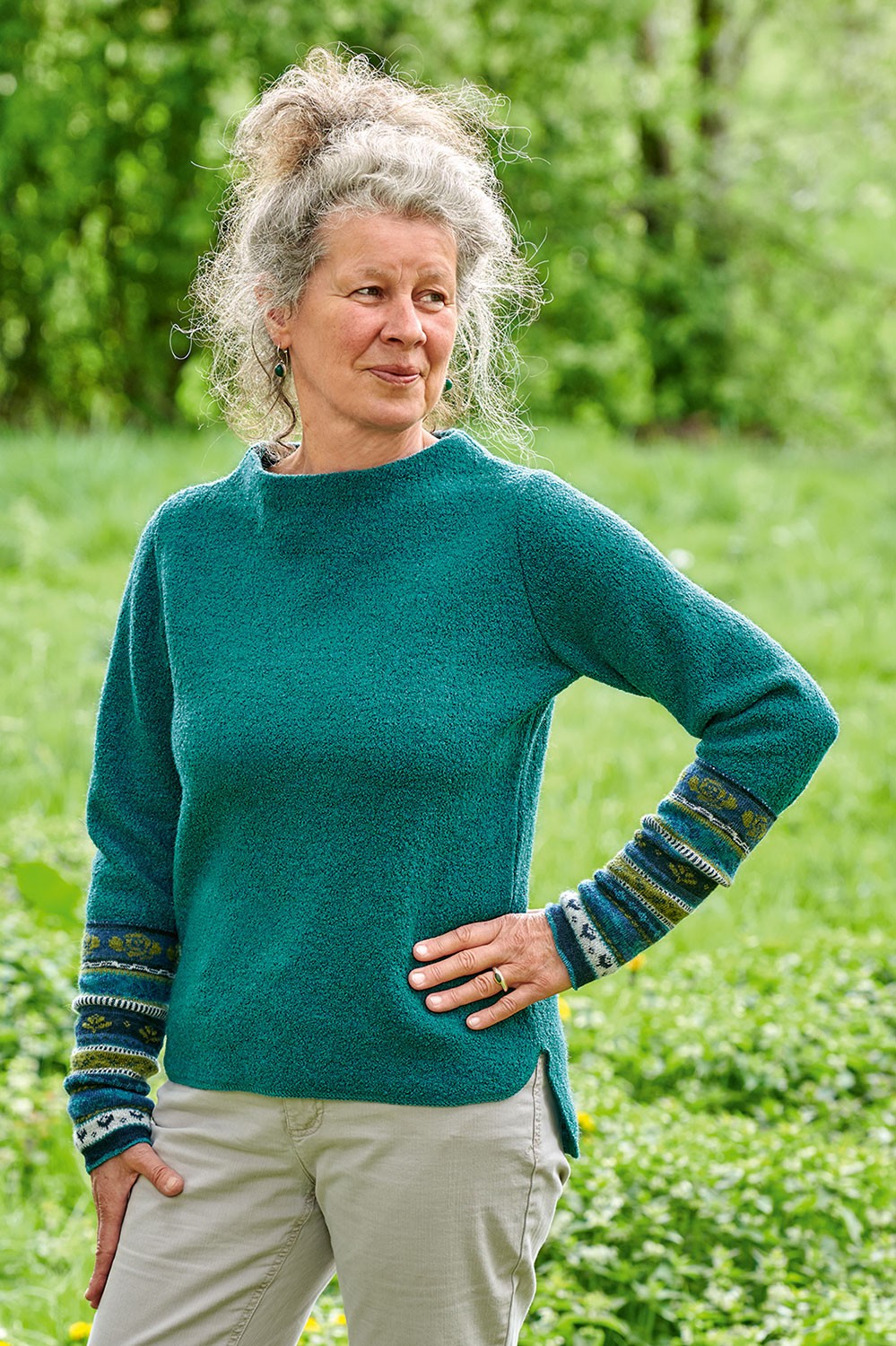 Frau mit türkisem Wollshirt trägt blau grün gemusterte Armstulpen aus bio Wolle (kbT)