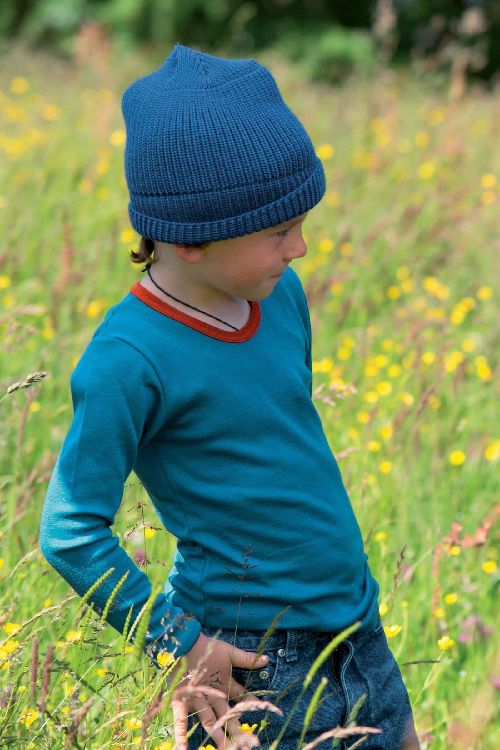 Junge trägt türkises Langarmshirt mit orangem Kragen aus bio Wolle (kbT) und Seide
