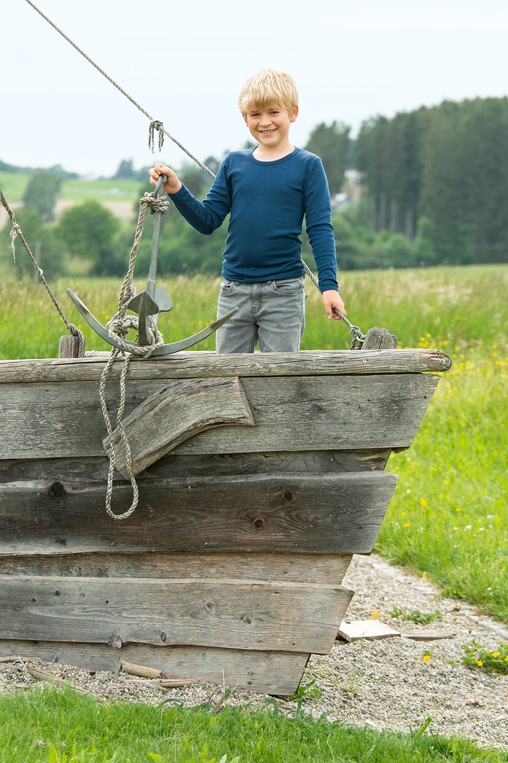 Kindershirt einfarbig Langarm mit Bio-Fasern Junge spielt auf Holzschiff und trägt ein dunkelblaues Langarmshirt aus bio Wolle (kbT) und Seide