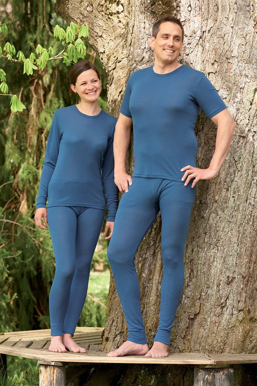 Mann und Frau stehen vor einem Baum und tragen dunkelblaue lange Unterhosen aus bio Wolle (kbT) und Seide und Shirts