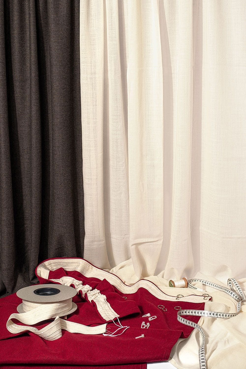 Gardinenband naturweiß Gardinenband aus Baumwolle naturweiß vor hängenden Gardinen auf rotem Stoff