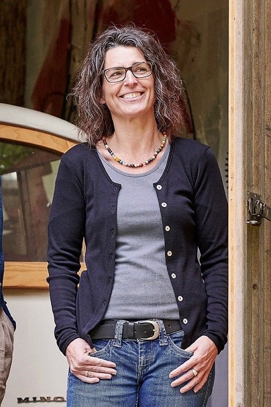 Frau trägt graues Shirt und schwarzer Cardigan mit Knöpfen aus bio Wolle (kbT) und Elasthan