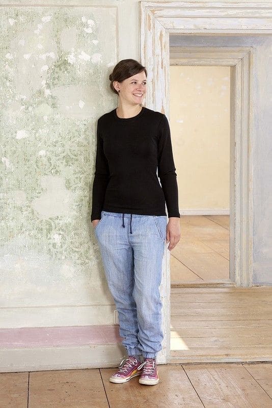 Frau trägt schwarzes Langarmshirt aus bio Wolle (kbT) und Seide mit blauer Jeanshose