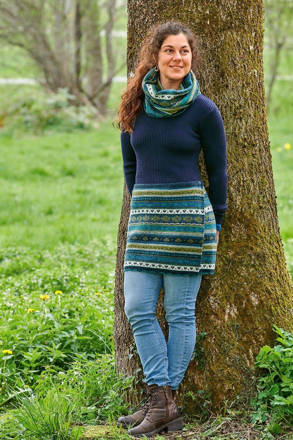 Frau mit blauem Rippshirt trägt blau grün gemusterten Loopschal aus bio Wolle (kbT) und gemusterten Cacheur