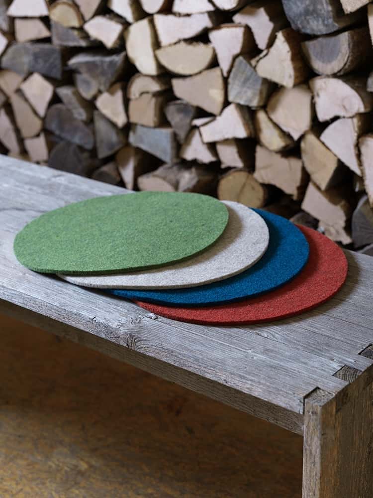 runde Finkhof-Sitzauflagen in verschiedenen Farben aus bio Wolle (kbT) auf einer Holzbank