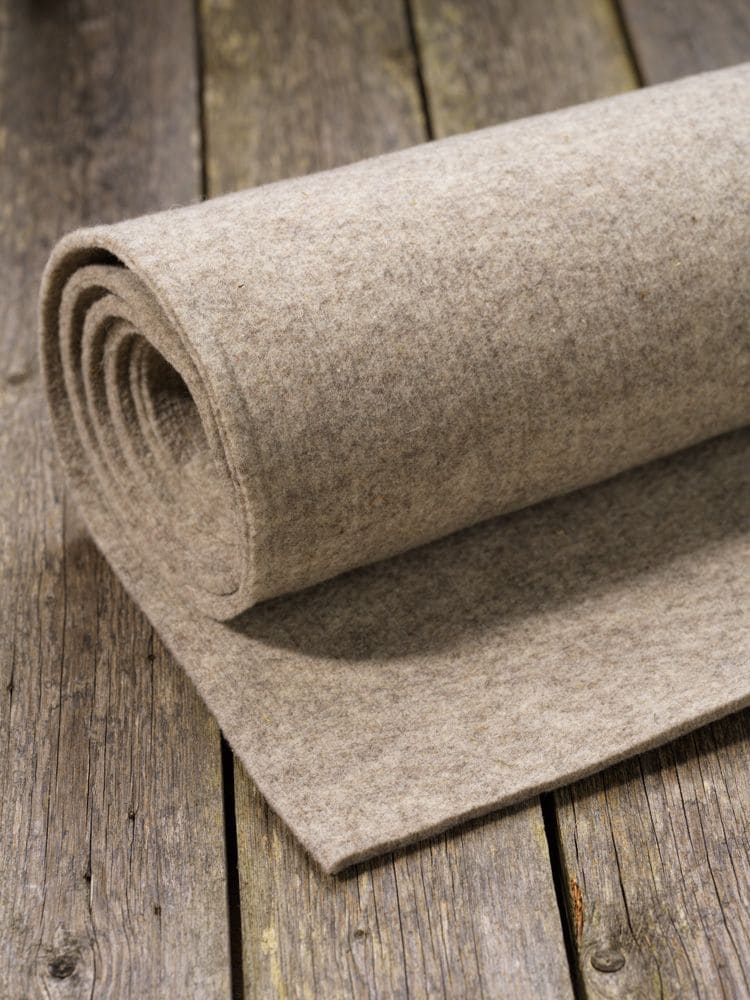 Finkhof-Nadelfilz grau graue Rolle Finkhof Nadelfilz aus bio Wolle (kbT) auf braunem Holzboden