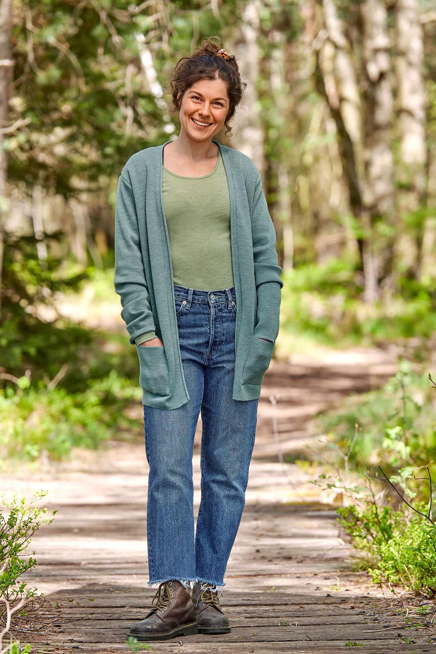 Long-Cardigan aus Bio-Merinowolle aqua Gr. M Frau mit Jeans und grünem Shirt trägt blauen langen Cardigan aus bio Wolle (kbT)