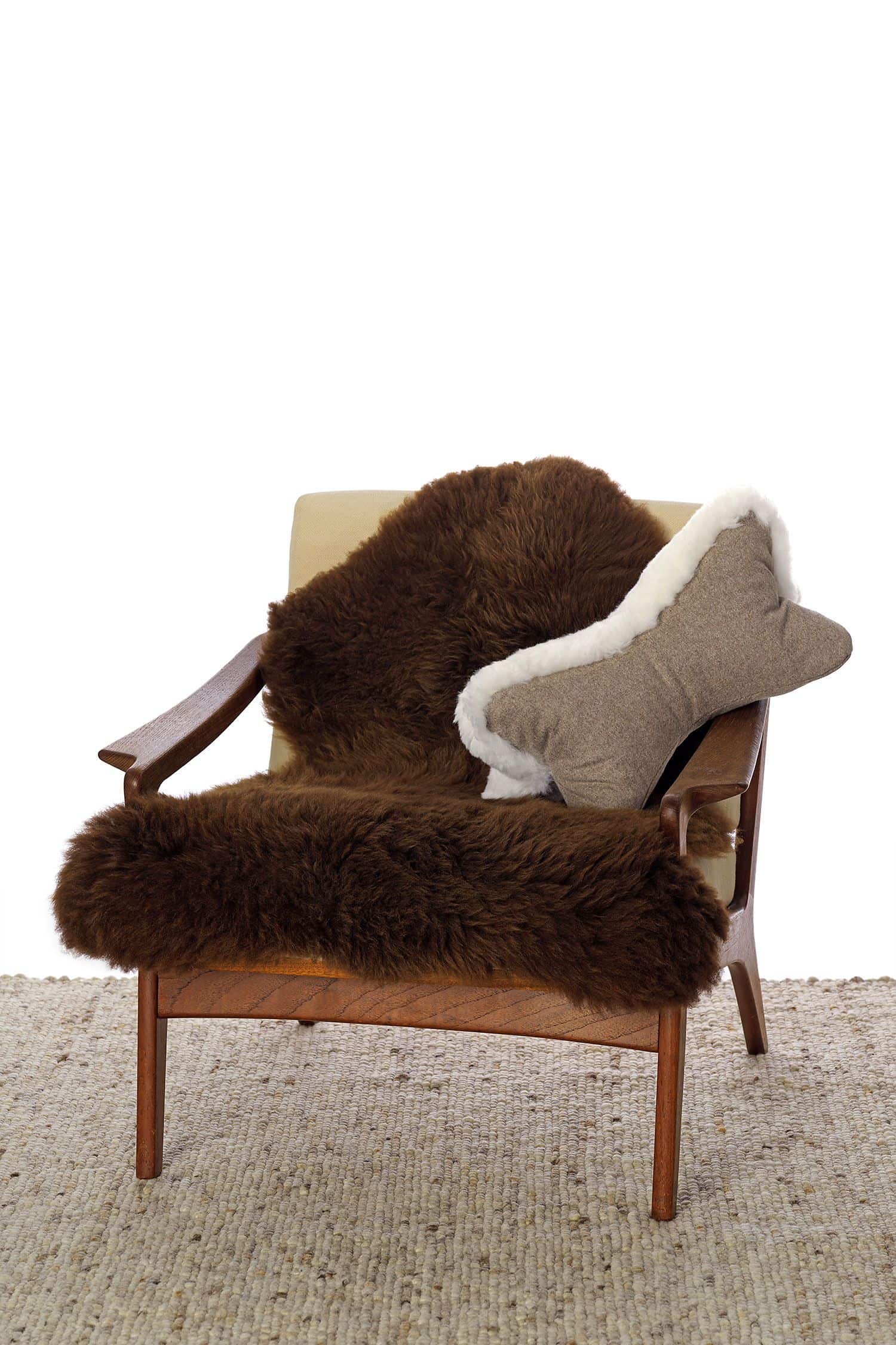 Leseknochen aus bio Loden (kbT) und weißem pflanzlich gegerbtem Schaffell vom Finkhof auf Sessel mit braunem Fell