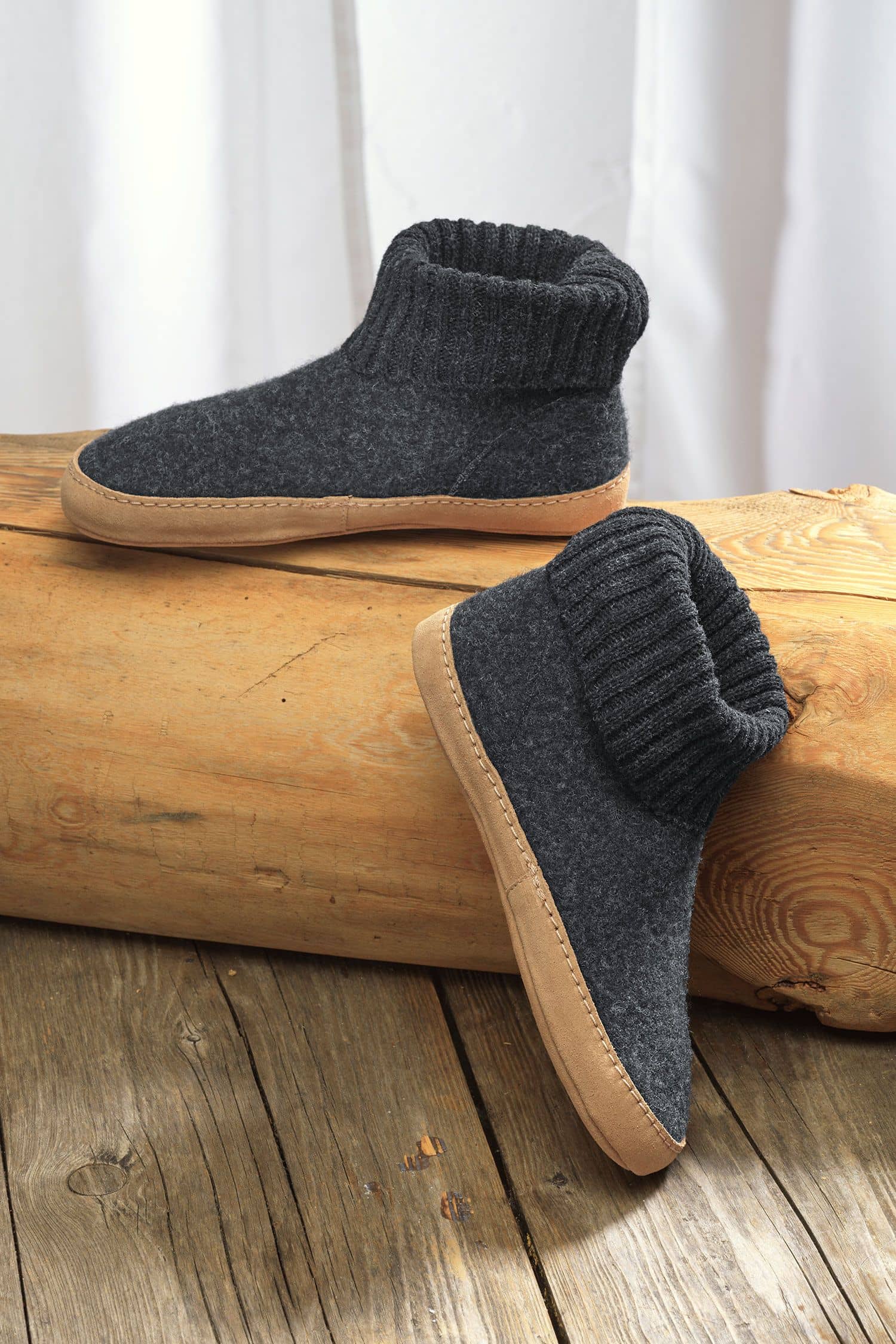 Finkhof-Hüttenschuhe mit Ledersohle gefärbt Paar dunkelgraue Finkhof Hüttenschuhe aus bio Wolle (kbT) und einer Sohle aus pflanzlich gegerbtem Rindsleder auf Baumstamm