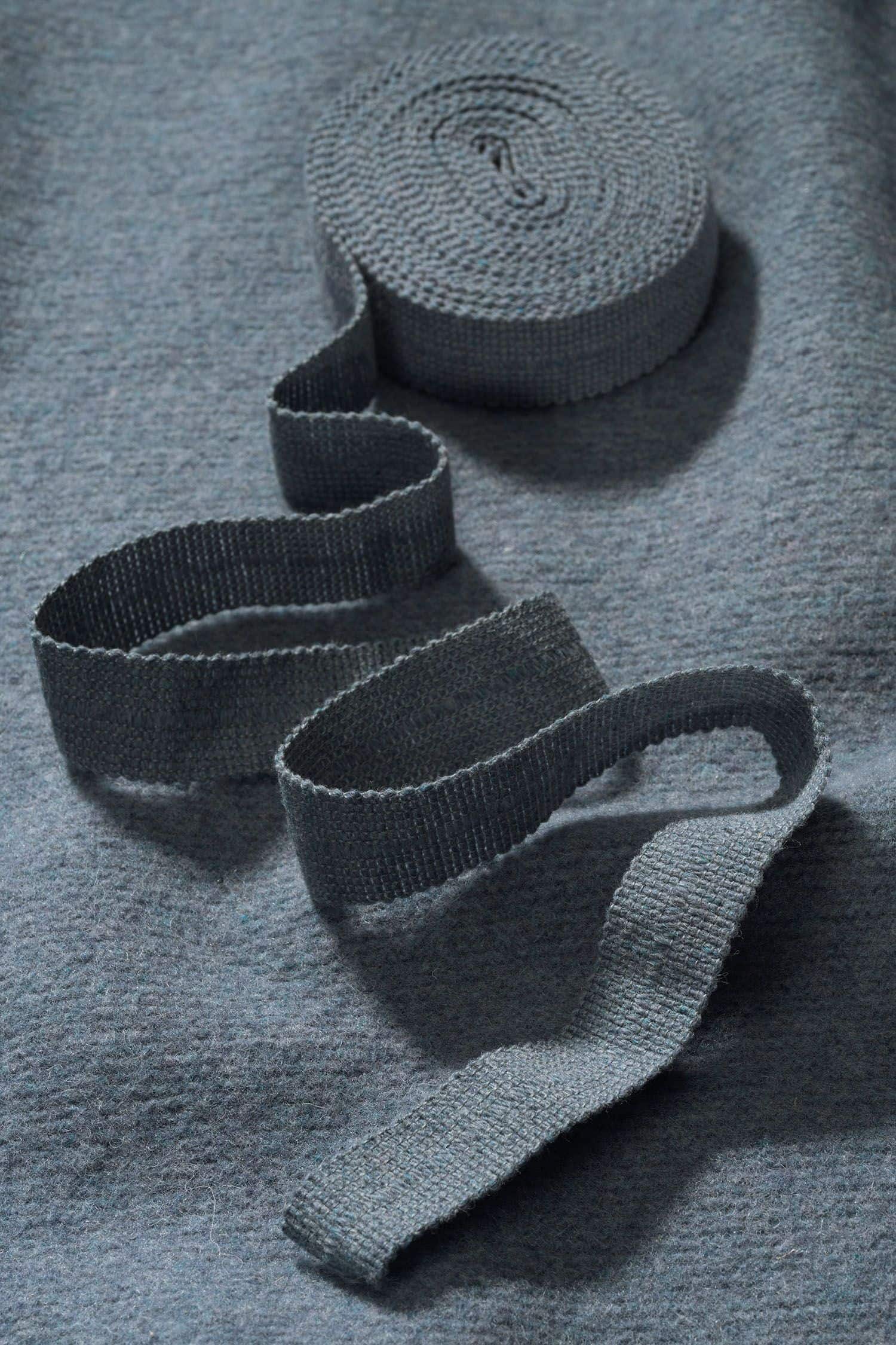 Finkhof-Web-Einfassband gefärbt rauchblau rauchblaues Einfassband aus bio Wolle (kbT) vom Finkstoff aufgerollt auf rauchblauem Stoff