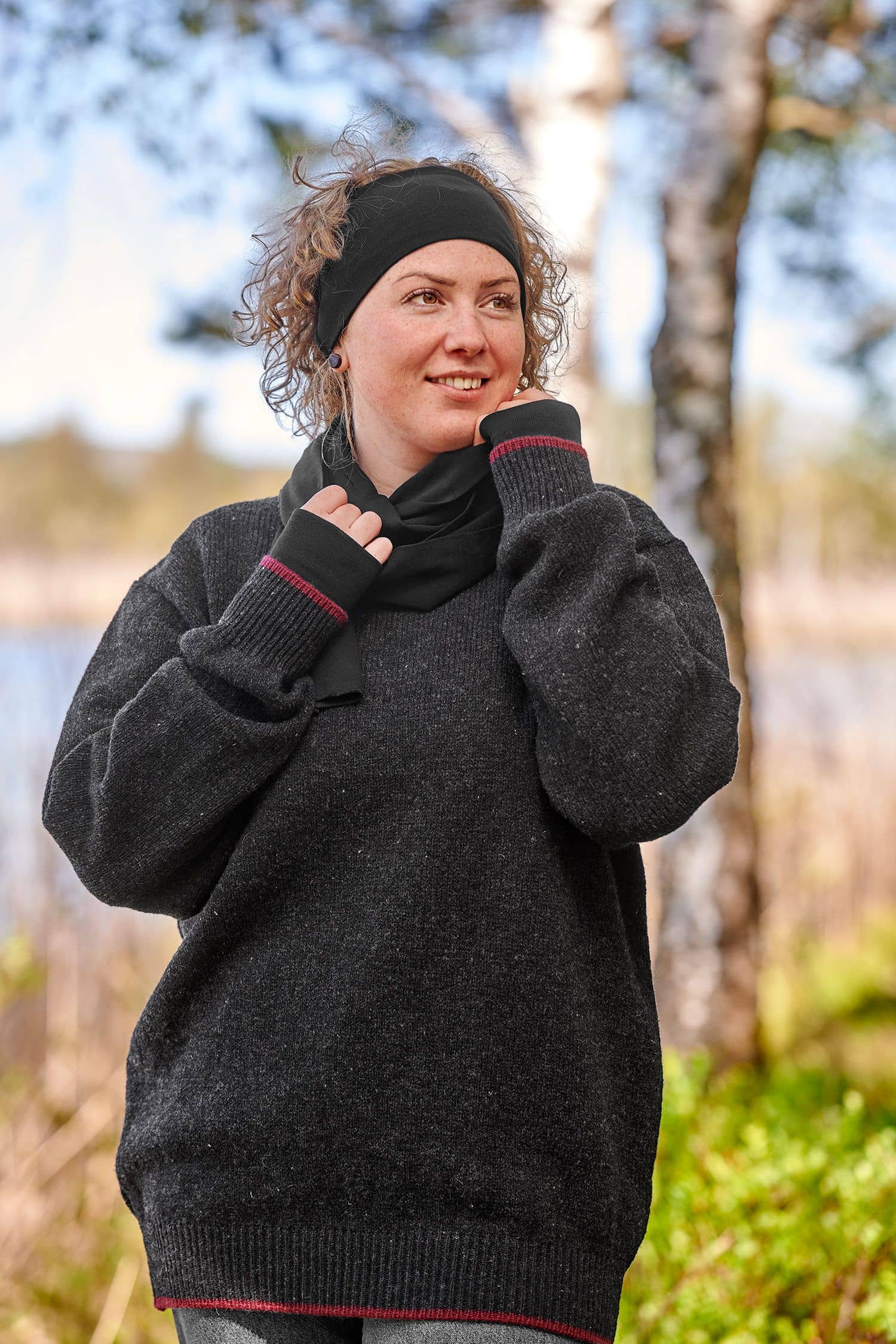 Frau mit grauem Pulli trägt schwarze Pulswärmer aus bio Wolle (kbT) und Seide mit Schal und Stirnband