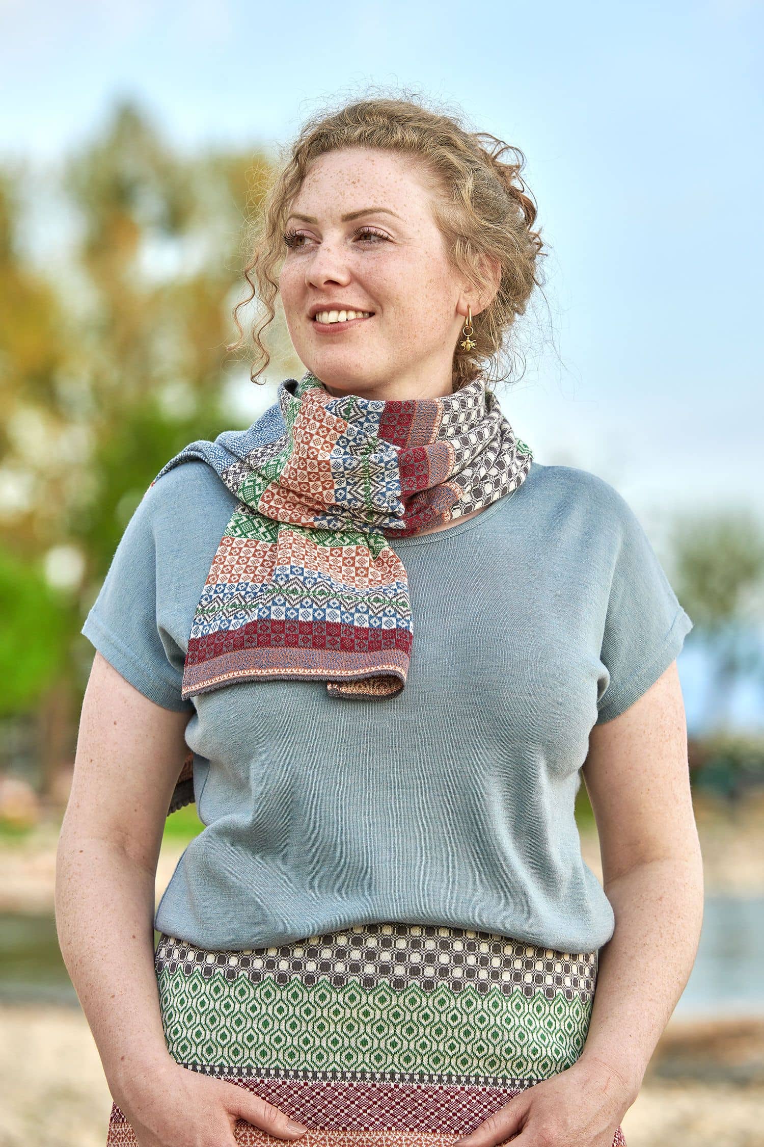 Frau trägt gemusterten Strickschal aus bio Baumwolle (kbA), einen Rock und ein Shirt