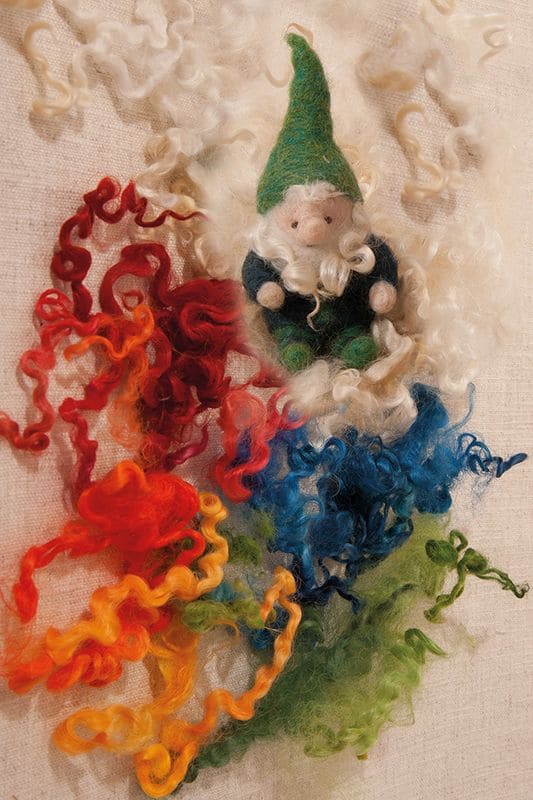 Wolllocken grüner Zwerg sitzt in bunten Wolllocken