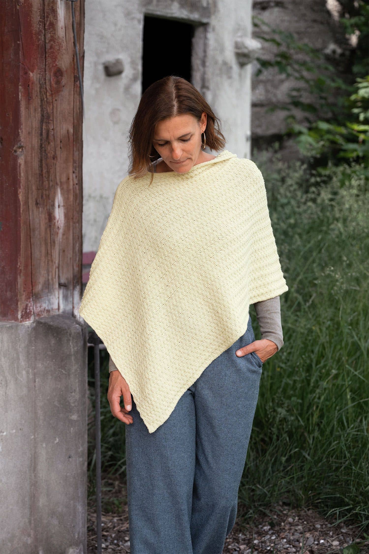 Frau trägt naturweißen Poncho mit Stoffhose als Beispielprojekt aus dem Buch ,,Rechte Masche linke Masche"