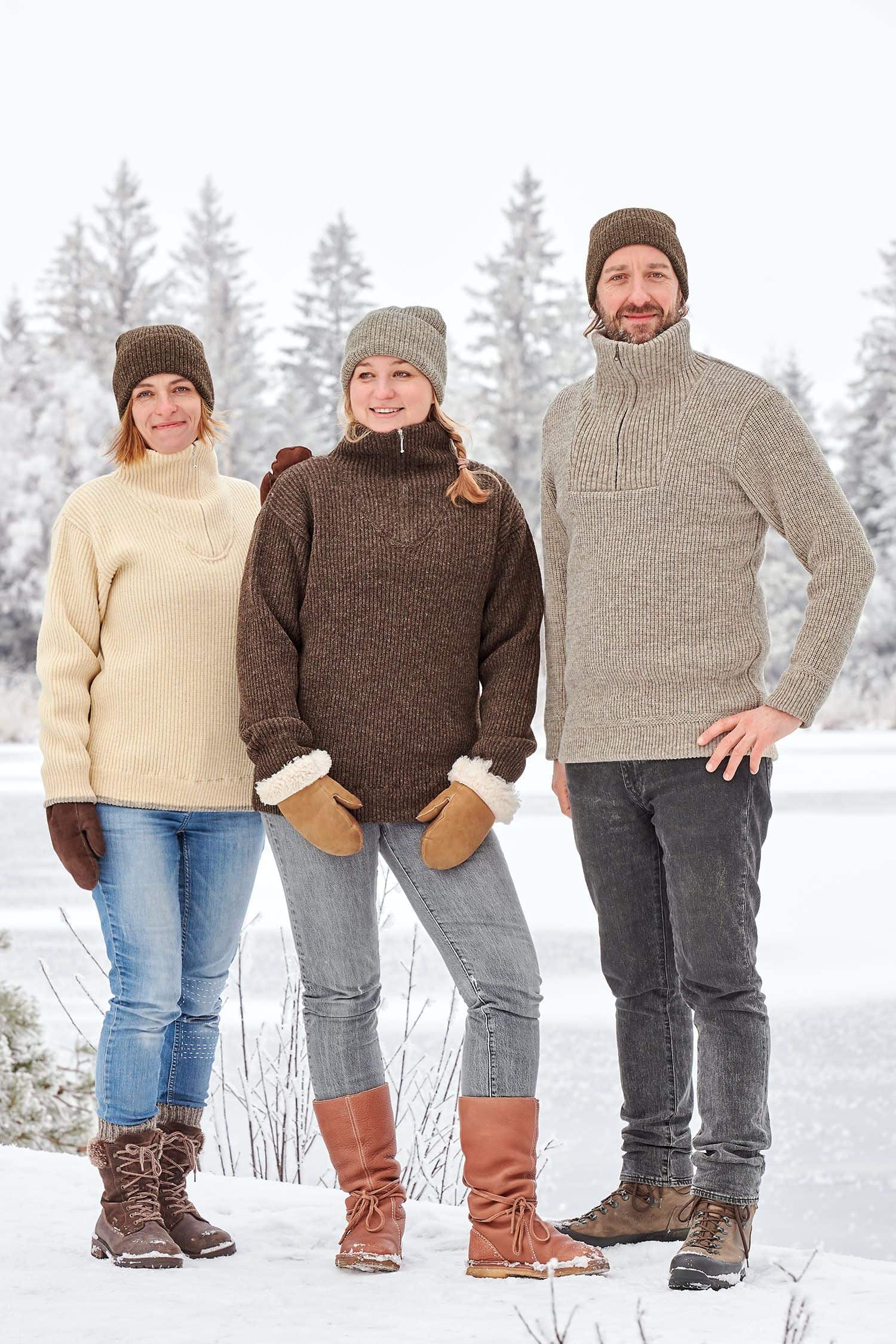 Finkhof-Troyer Mann und Frauen tragen Finkhof Troyer aus bio Fuchsschafwolle (kbT) vom Finkhof mit Mützen in Winterlandschaft mit Schnee