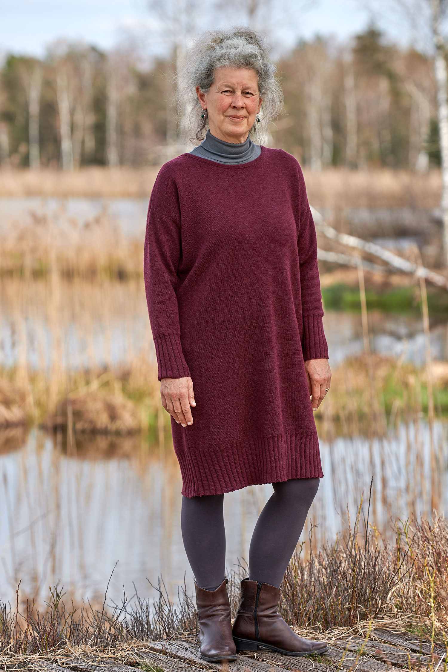 Frau trägt burgunderrotes Strickkleid aus bio Wolle (kbT) mit einen grauen Rollkragenshirt