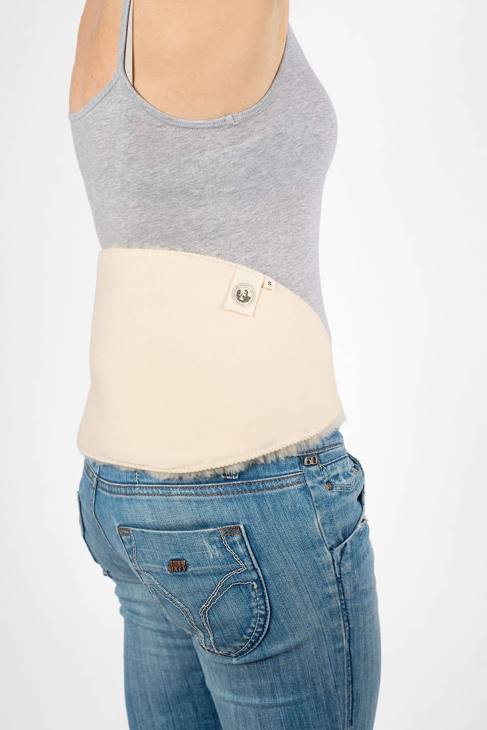 Model von Seite mit grauem Top, Jeans und weißem relugan gegerbtem Finkhof Rückenwärmer aus Schaffell und kbA Baumwolle