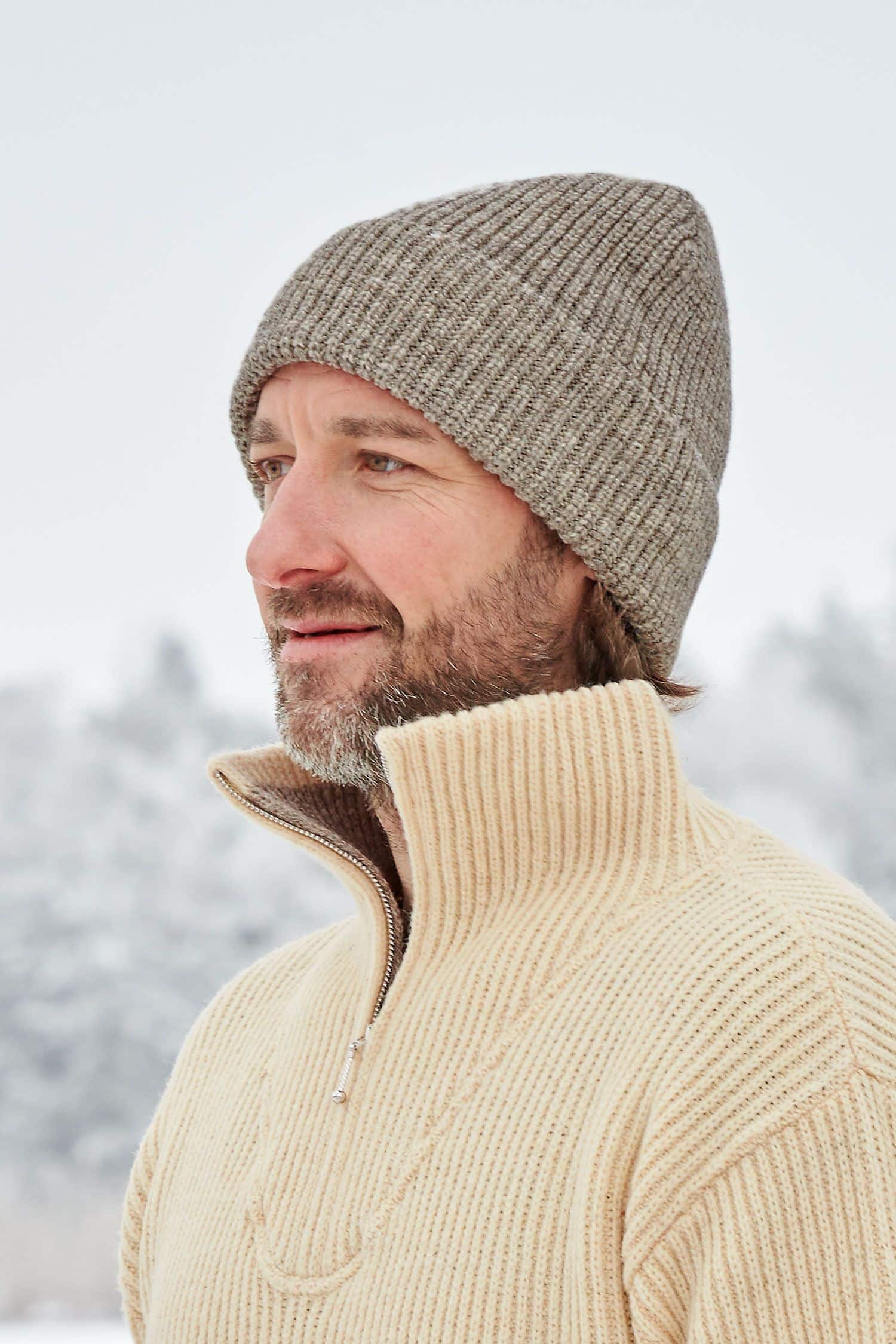 Mann trägt graue Finkhof Mütze aus bio Wolle (kbT) und naturweißen Finkhof Troyer