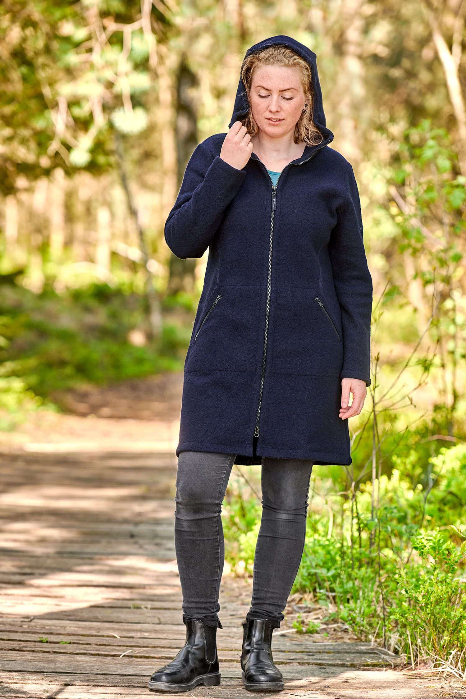 Frau mit schwarzer Jeans hat die Kapuze eines marineblauen Wollmantels auf