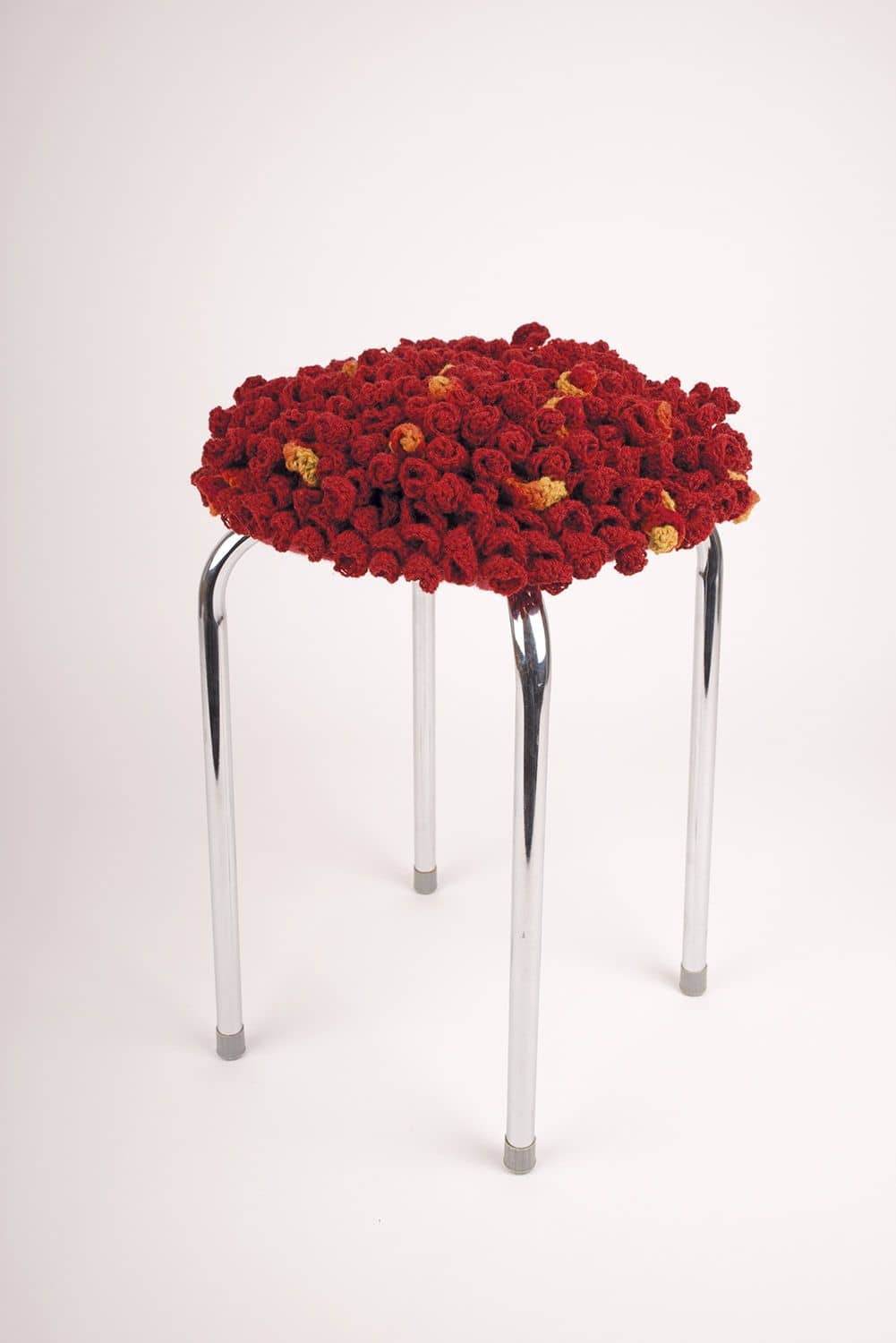 Hocker mit Bezug aus rot orangenen Häkelspiralen