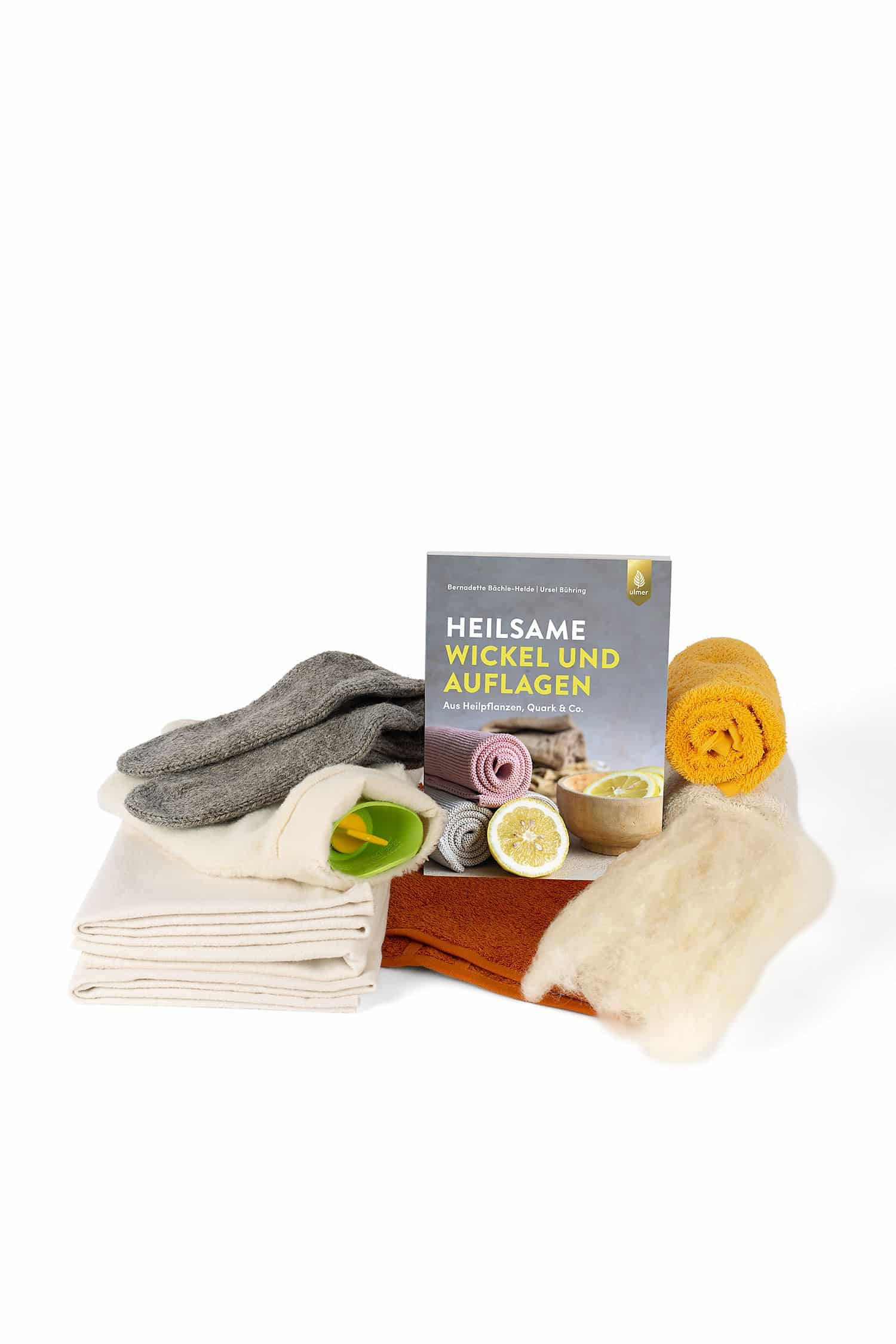 Heilsame Wickel und Auflagen Stimmungsbild rund um das Buch ,,Heilsame Wickel und Auflagen" mit Vließ, Fettwolle, Socken und einer Wärmflasche