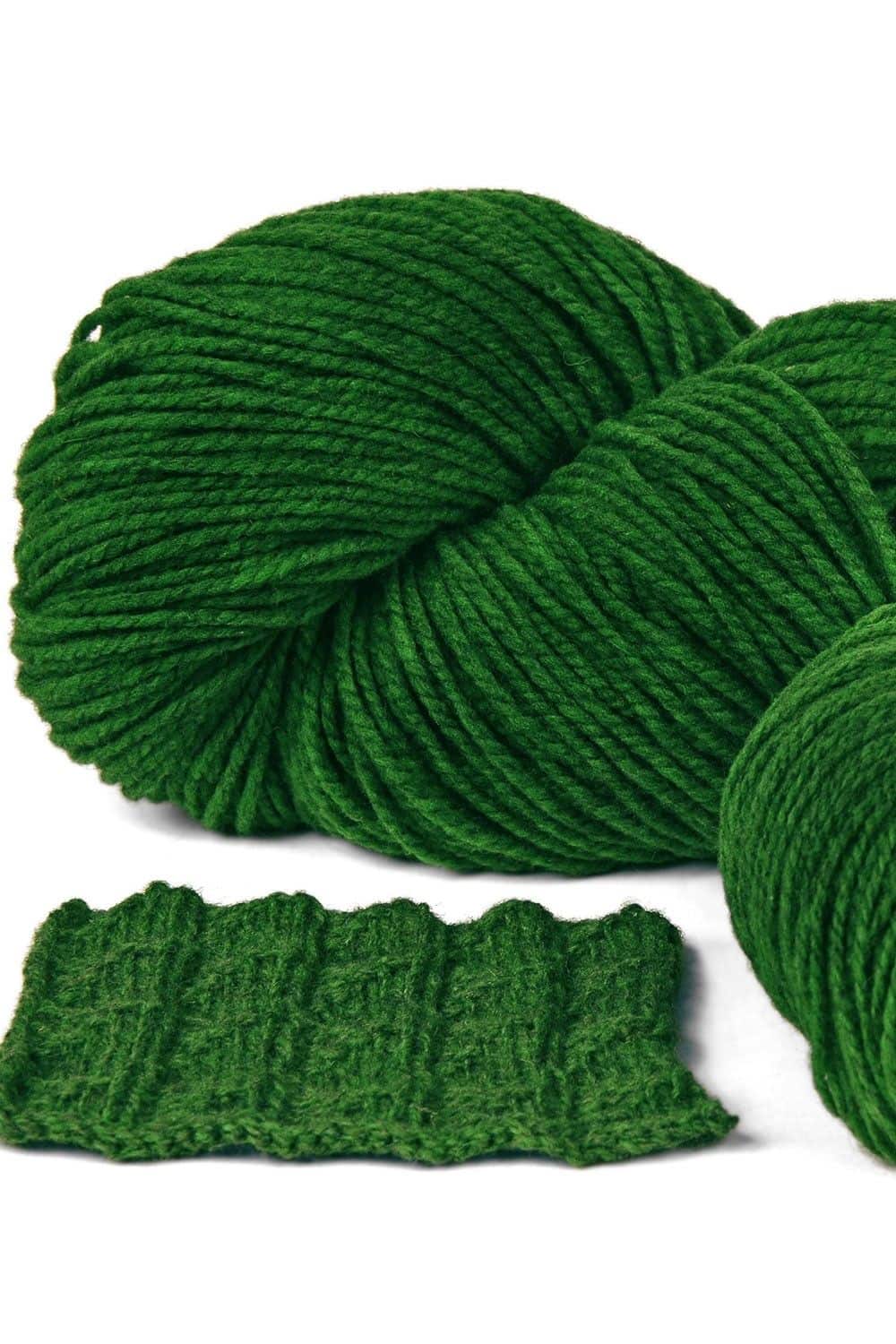 Finkhof Merinowolle dick gefärbt dunkelgrün dicke dunkelgrüne Finkhof Merinowolle aus bio Wolle (kbT) mit Strickstück davor, weißer Untergrund