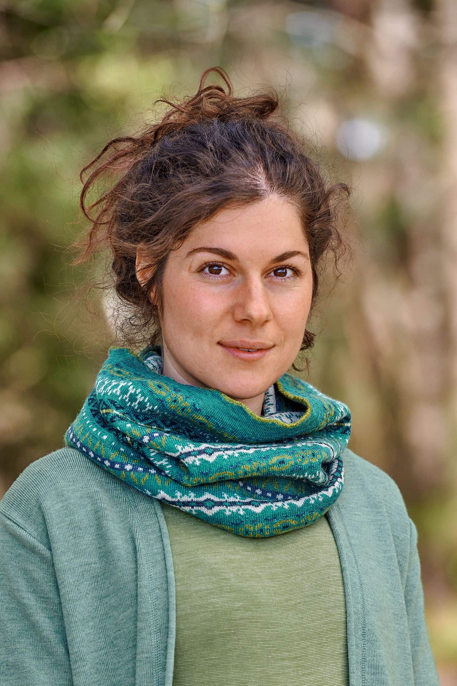 Loop Nordic türkis Frau mit grünem Shirt und blauem Cardigan trägt türkisen Loopschal mit nordischem Muster aus bio Wolle (kbT)