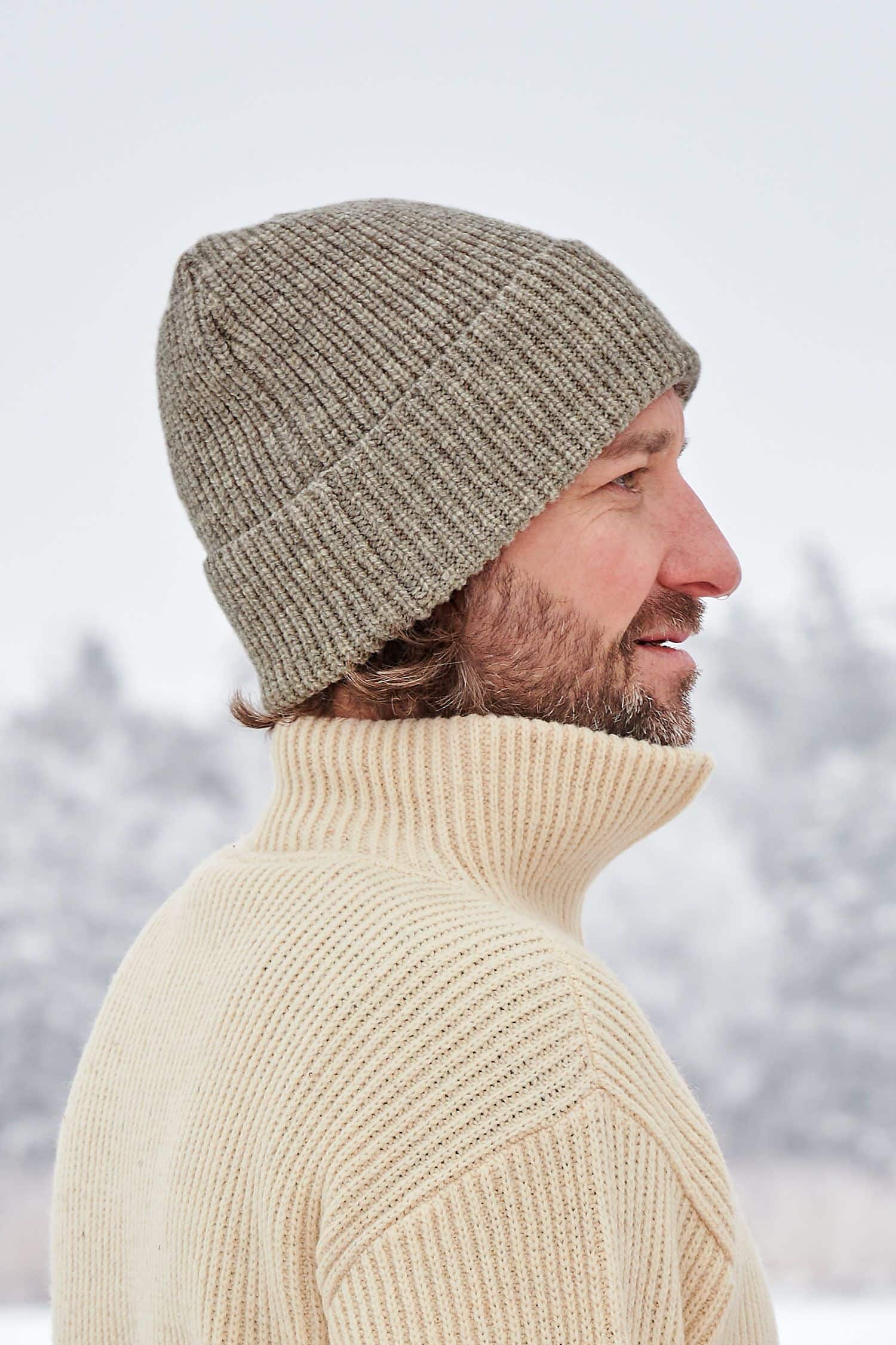 Mann trägt graue Finkhof Mütze aus bio Wolle (kbT) und naturweißen Finkhof Troyer